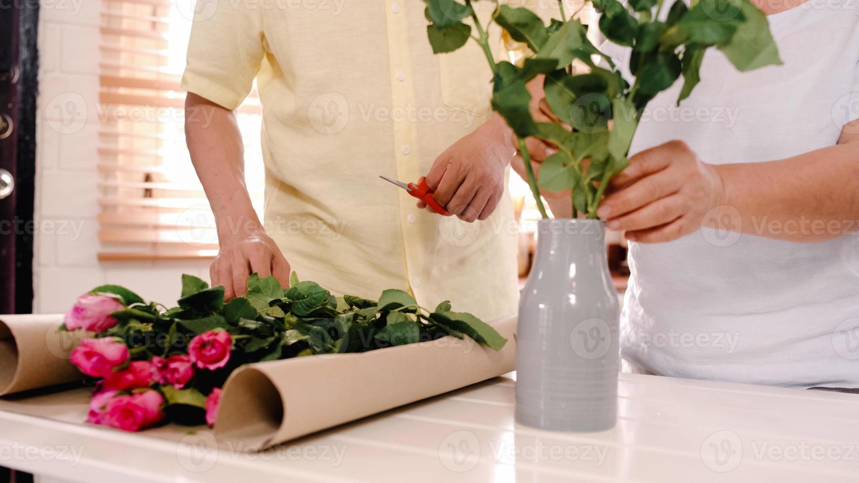 Aziatische bejaarde echtpaar boeket bloemen maken op een houten tafel in de keuken thuis. Chinees zoet senior paar dat tijd gebruikt, ontspant samen thuis. levensstijl senior paar thuis concept. foto