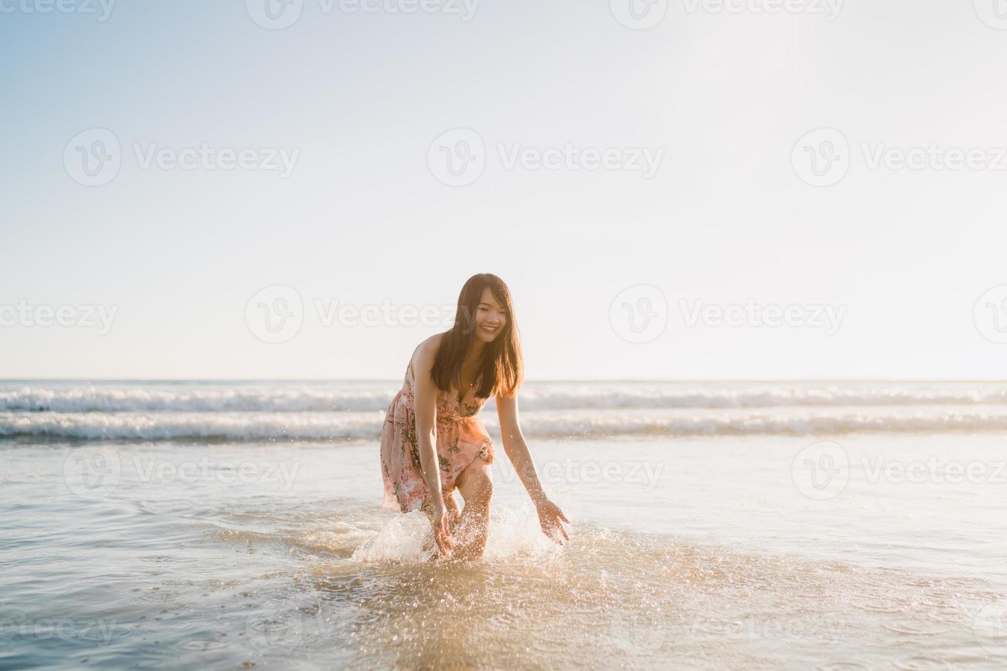 jonge Aziatische vrouw lopen op het strand. mooie vrouw gelukkig ontspannen wandelen op het strand in de buurt van de zee bij zonsondergang in de avond. levensstijl vrouwen reizen op strand concept. foto