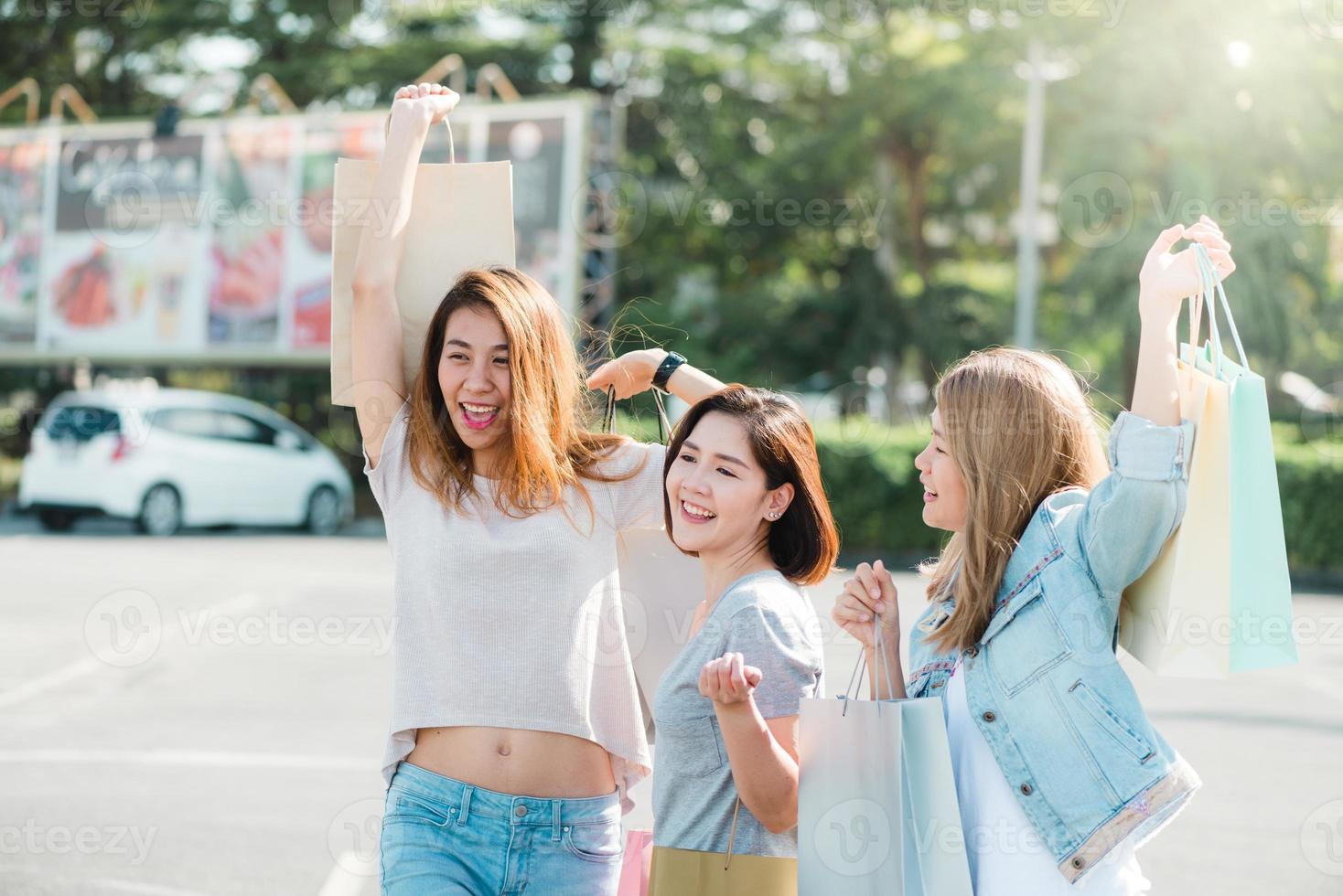 groep jonge aziatische vrouw winkelen in een openluchtmarkt met boodschappentassen in hun handen. jonge aziatische vrouwen laten zien wat ze in de boodschappentas hebben gekregen onder warm zonlicht. groep buiten winkelen concept. foto