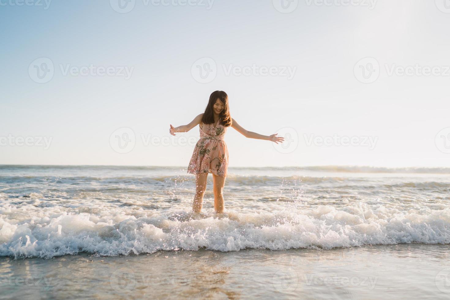 jonge Aziatische vrouw lopen op het strand. mooie vrouw gelukkig ontspannen wandelen op het strand in de buurt van de zee bij zonsondergang in de avond. levensstijl vrouwen reizen op strand concept. foto