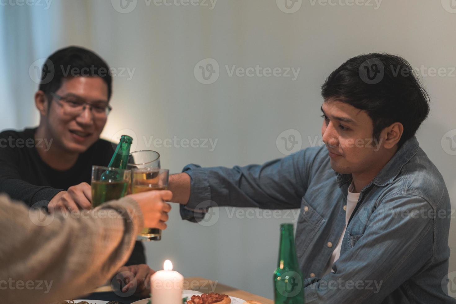 prettige kerstdagen en gelukkig nieuwjaar jonge vriendengroep die thuis eet. aziatisch familiefeest met bier en pizza eten in de buurt van kerstboom in huis in de nacht. viering vakantie en saamhorigheid. foto