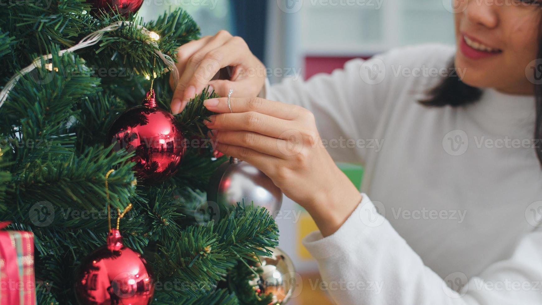 aziatische vrouwen versieren kerstboom op kerstfestival. vrouwelijke tiener gelukkig lachend vieren kerst wintervakantie in de woonkamer thuis. Close-up shot. foto