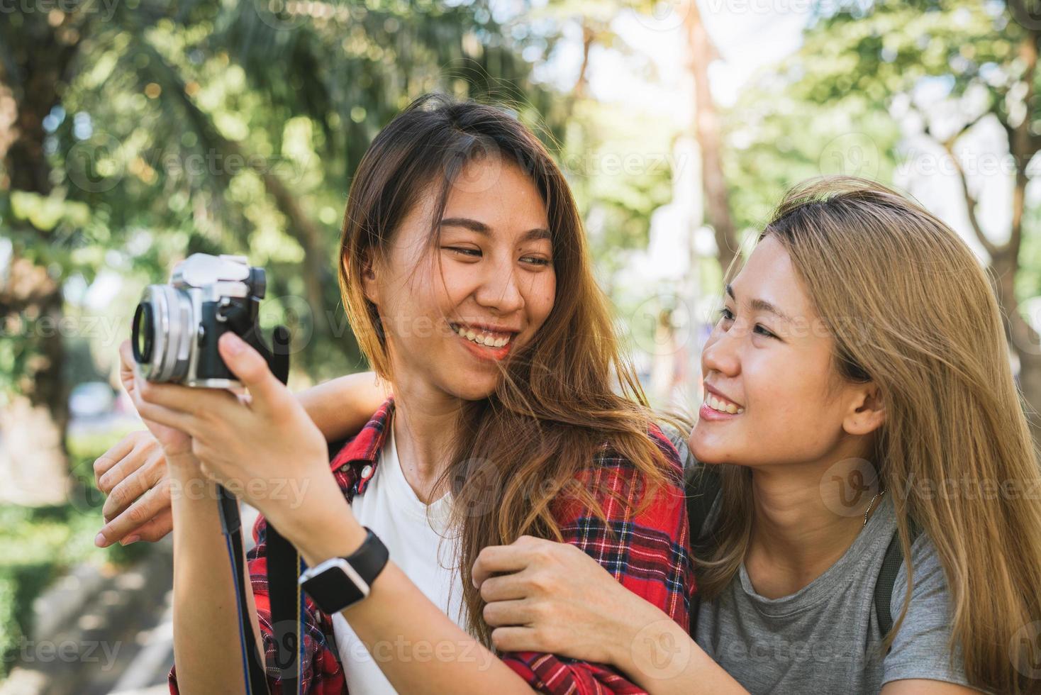 gelukkige mooie reiziger Aziatische vriend vrouwen dragen rugzak. jonge vrolijke vriend aziatische vrouwen die camera gebruiken om foto's te maken tijdens stadstour, vrolijke emoties. vrouwen levensstijl buiten in stadsconcept. foto