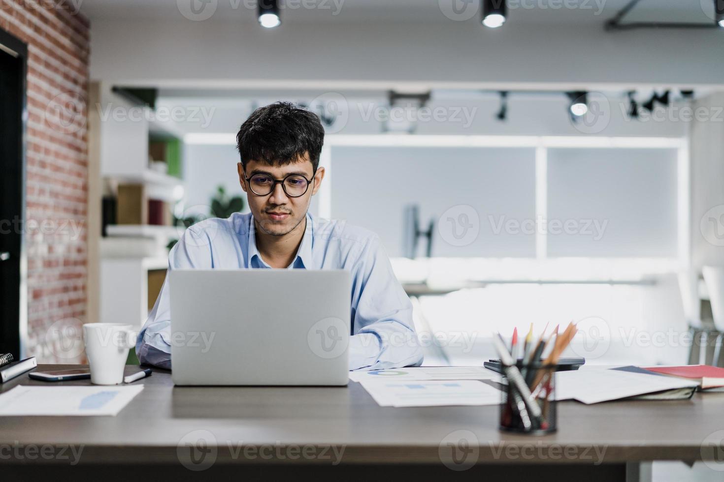 aziatische creatieve man tekening werkplan op karton. jonge professionele zakelijke man denkt en schrijft informatieherinnering op papier op baksteen, bedrijfssituatie, opstarten in loft-kantoorconcept. foto