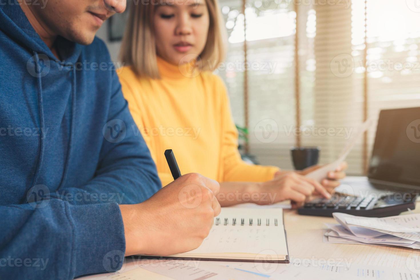 jong aziatisch stel dat de financiën beheert, hun bankrekeningen bekijkt met behulp van een laptopcomputer en rekenmachine in een modern huis. vrouw en man doen samen papierwerk, betalen online belastingen op notebook pc. foto