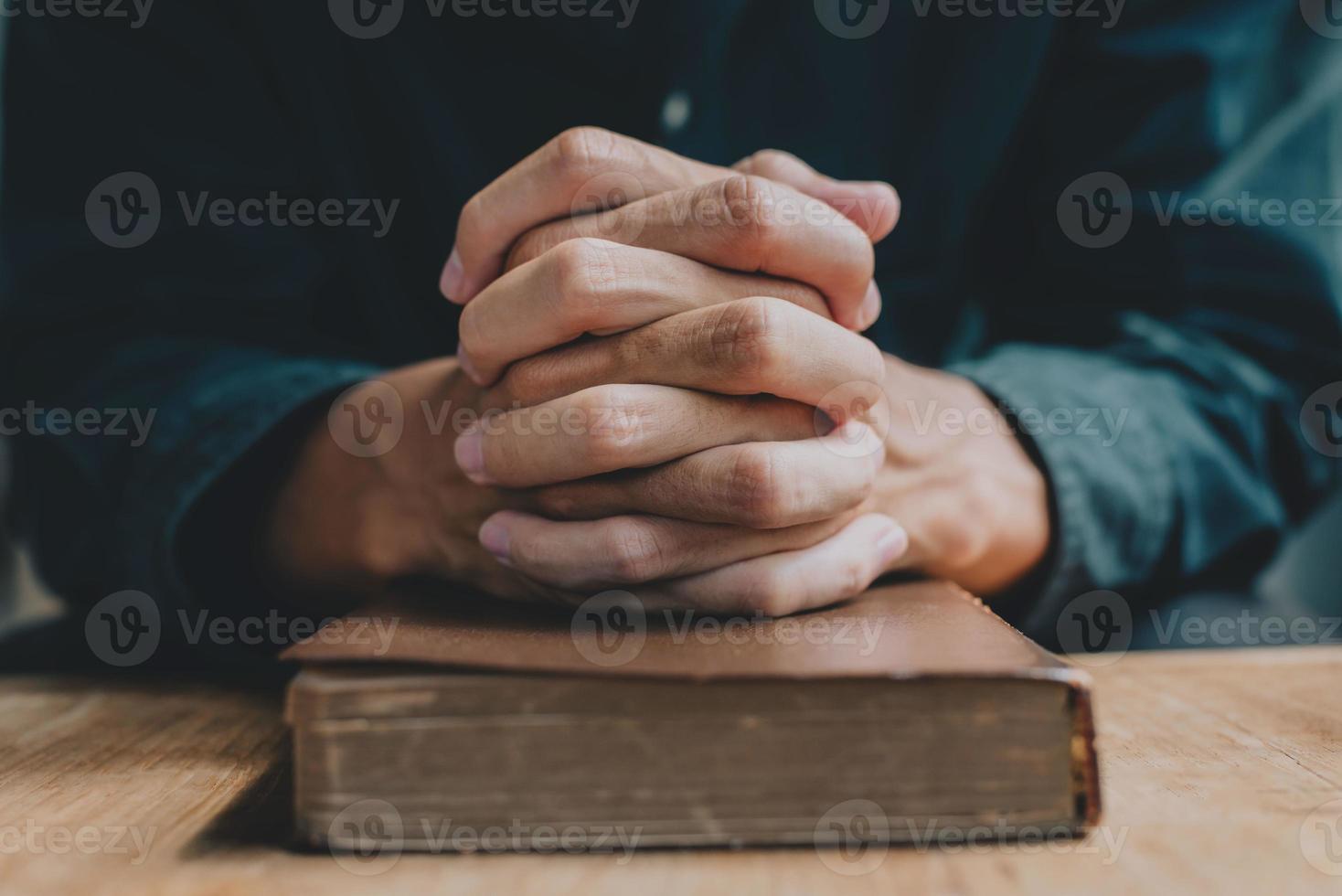 handen van een man die bidt over een bijbel staat voor geloof en spiritualiteit in het dagelijks leven. detailopname. foto