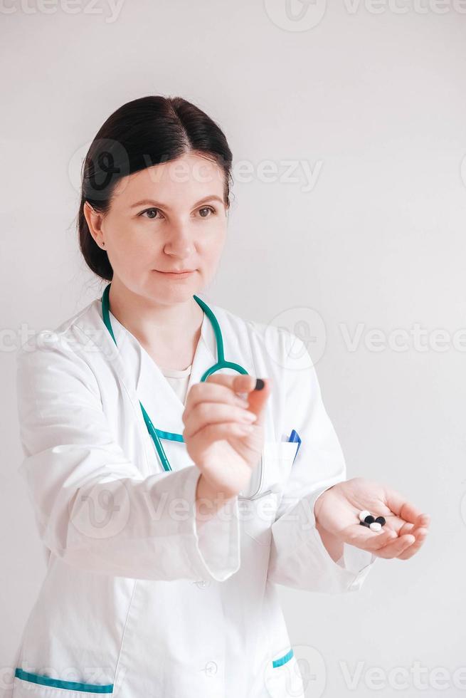 vrouw arts met pillen in haar handen op een witte achtergrond. het nemen van vitamines of medicijnen. kopiëren, lege ruimte voor tekst foto