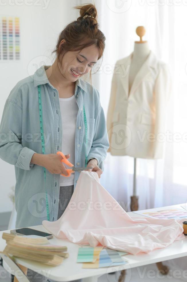 kleermakersvrouwen gebruiken schaar om stof op een designerbureau te knippen. foto