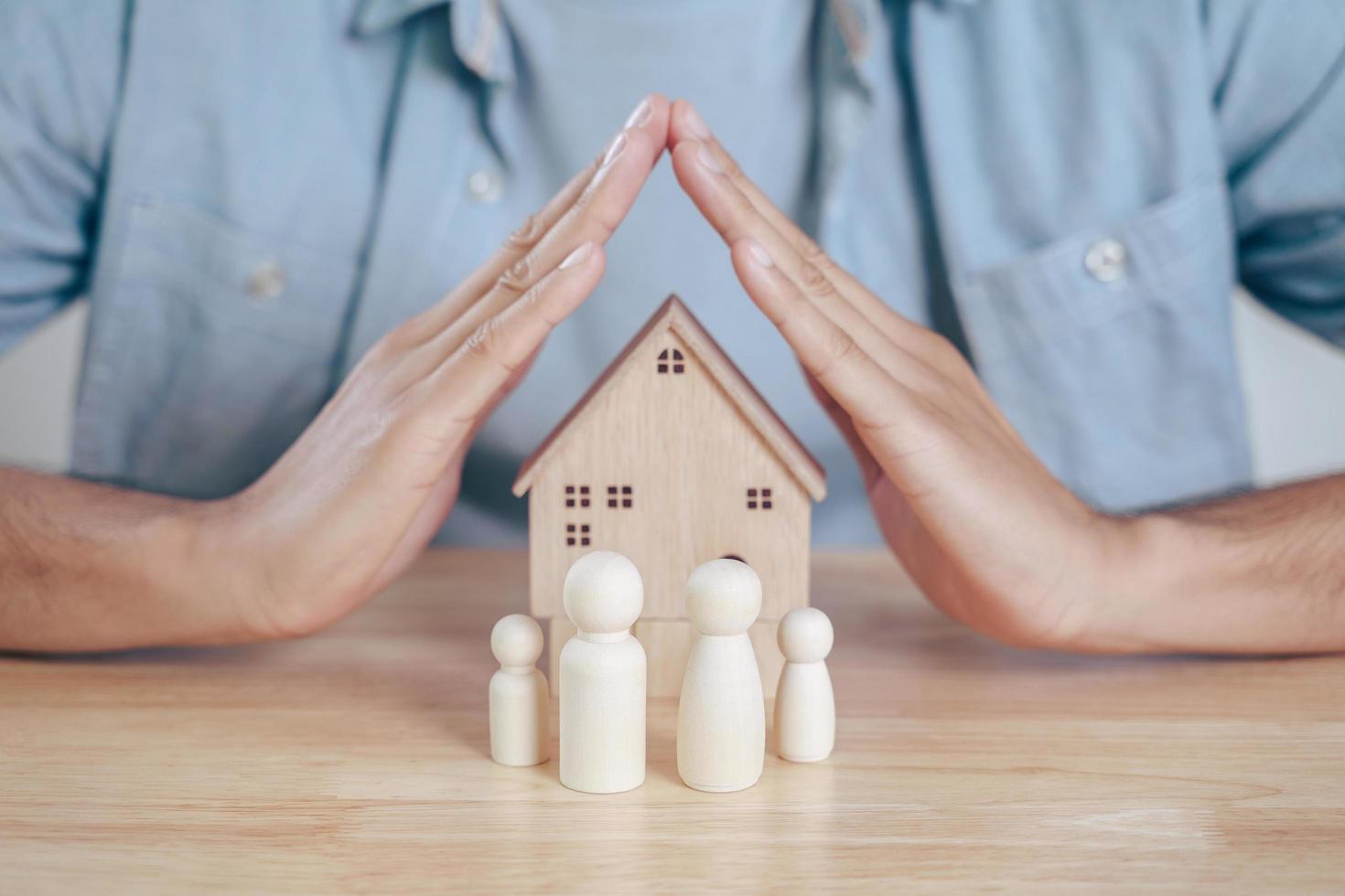 de man handen beschermen over houten poppetjes. planning, familie redden, gezondheidszorg en verzekeringen, geestelijke gezondheid van het gezin, internationale dag van het gezin foto