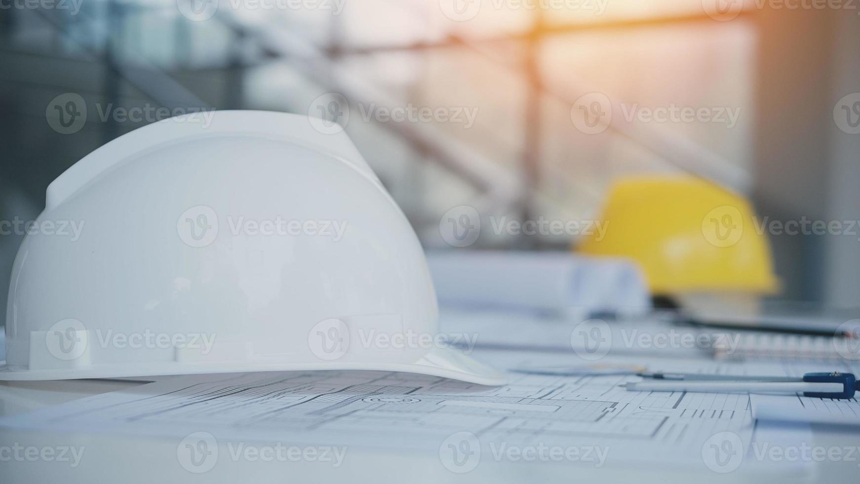 gele helm op tafel met blauwdrukken. veiligheidsproject van werkman als ingenieur of arbeider op betonnen vloer. foto