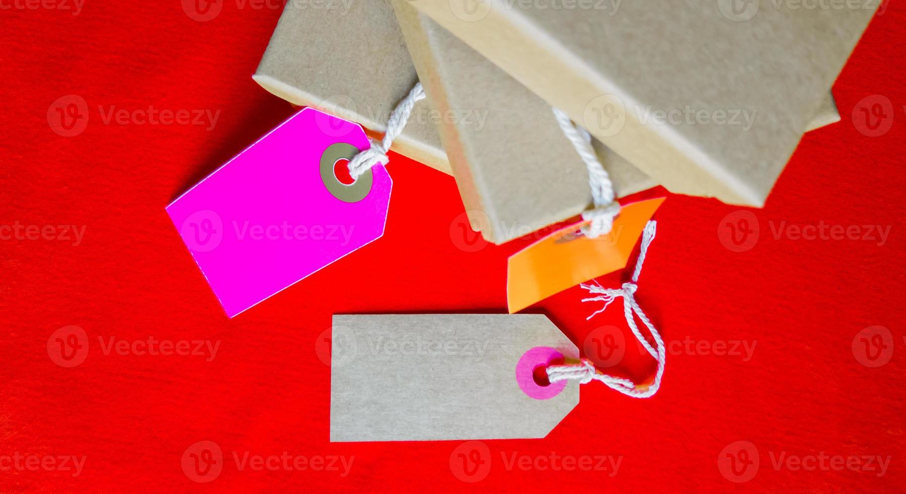 kartonnen dozen met een tag. bruine verpakkingsdoos met blanco label en kopieerruimte op rode achtergrond foto
