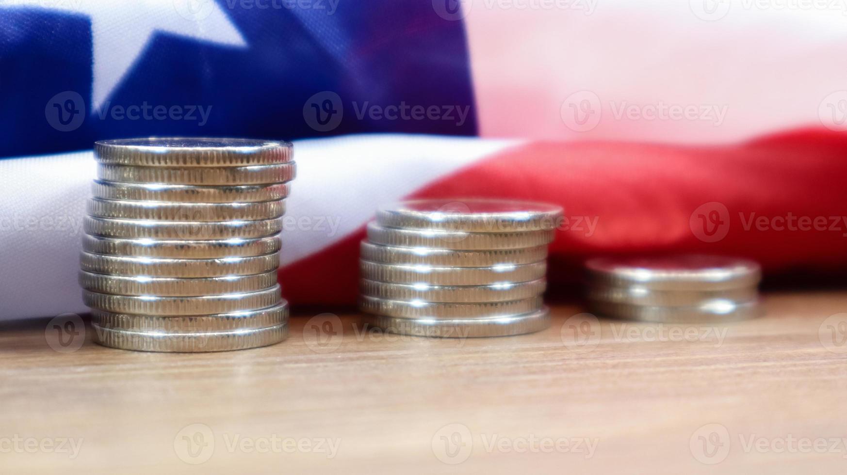 Amerikaanse munten met de vlag van de verenigde staten van amerika. investeringsconcept, zakelijke financiën en geld besparen. ons munten gestapeld tegen de achtergrond van de amerikaanse vlag. selectieve aandacht. foto