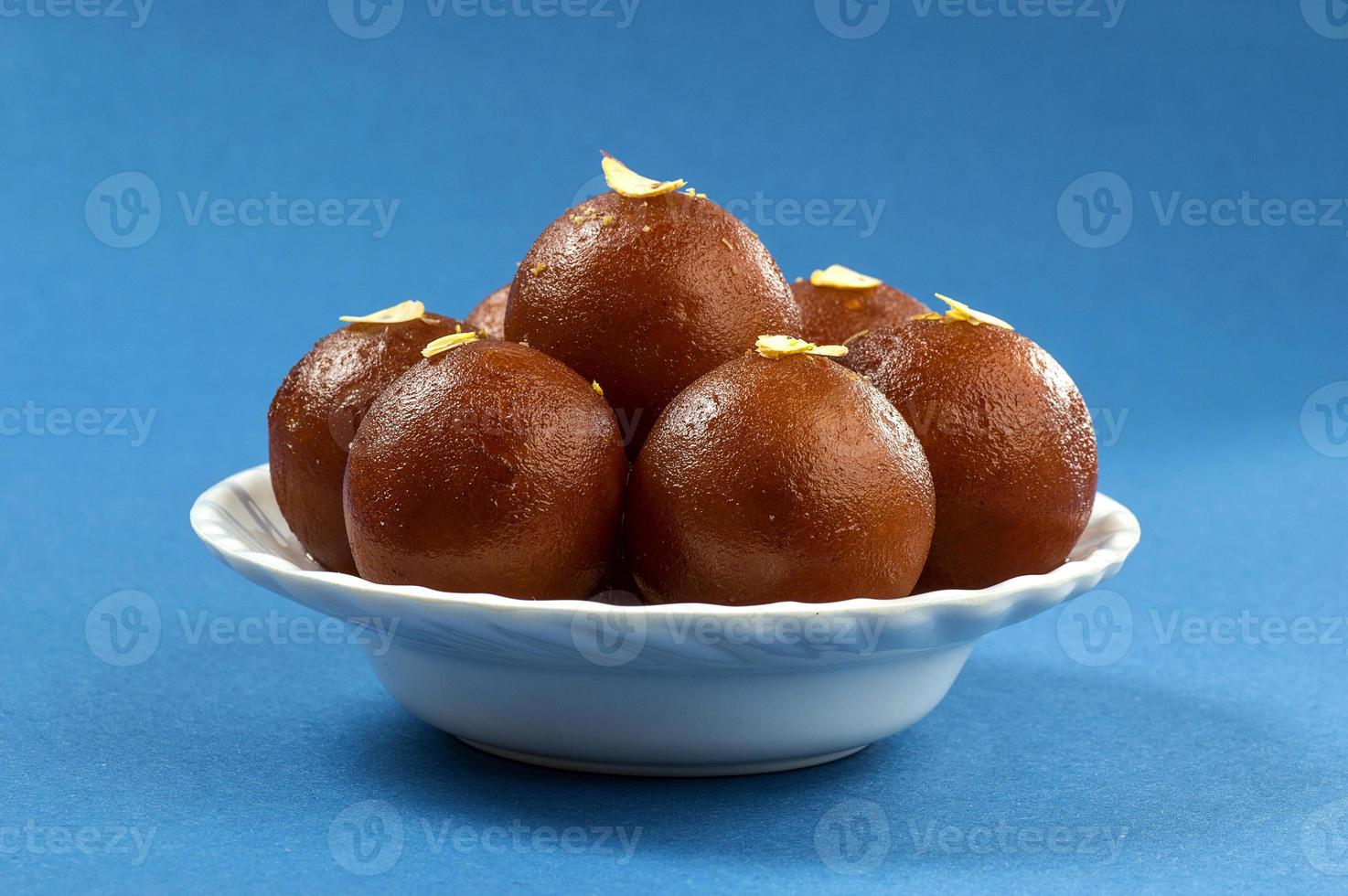 gulab jamun, Indiaas dessert met droge friut in witte kom met servet foto