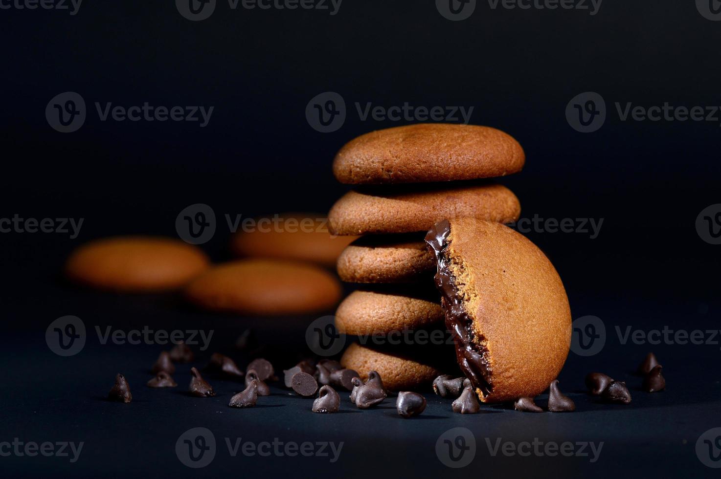 koekjes - stapel heerlijke roomkoekjes gevuld met chocoladeroom op zwarte achtergrond foto