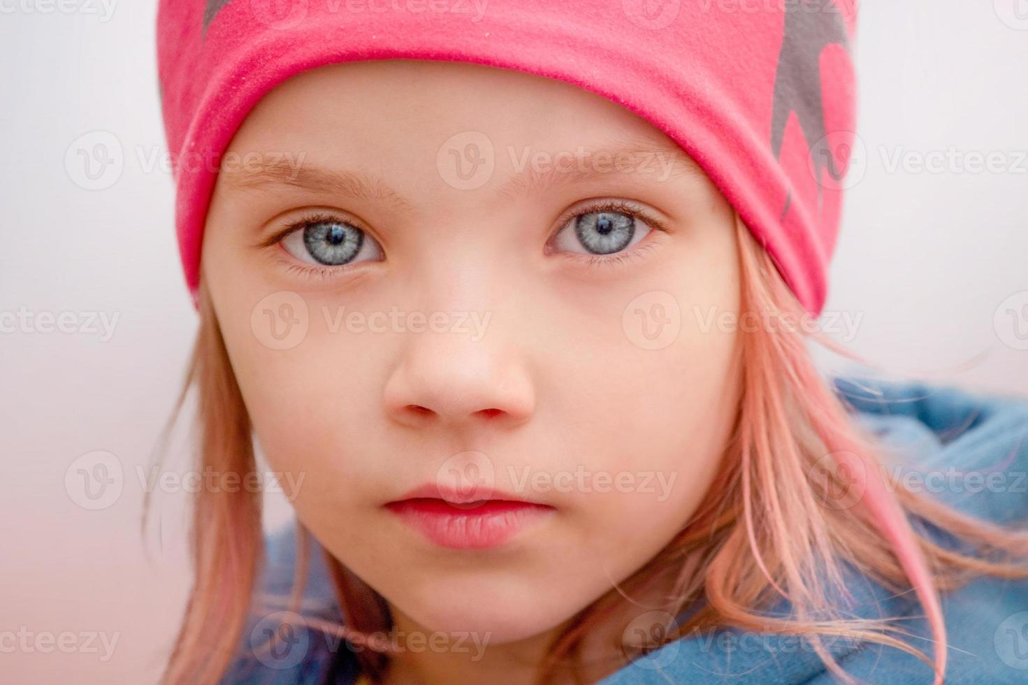 meisje met roze haren in een pet buitenshuis. klein meisje met blauwe ogen. foto