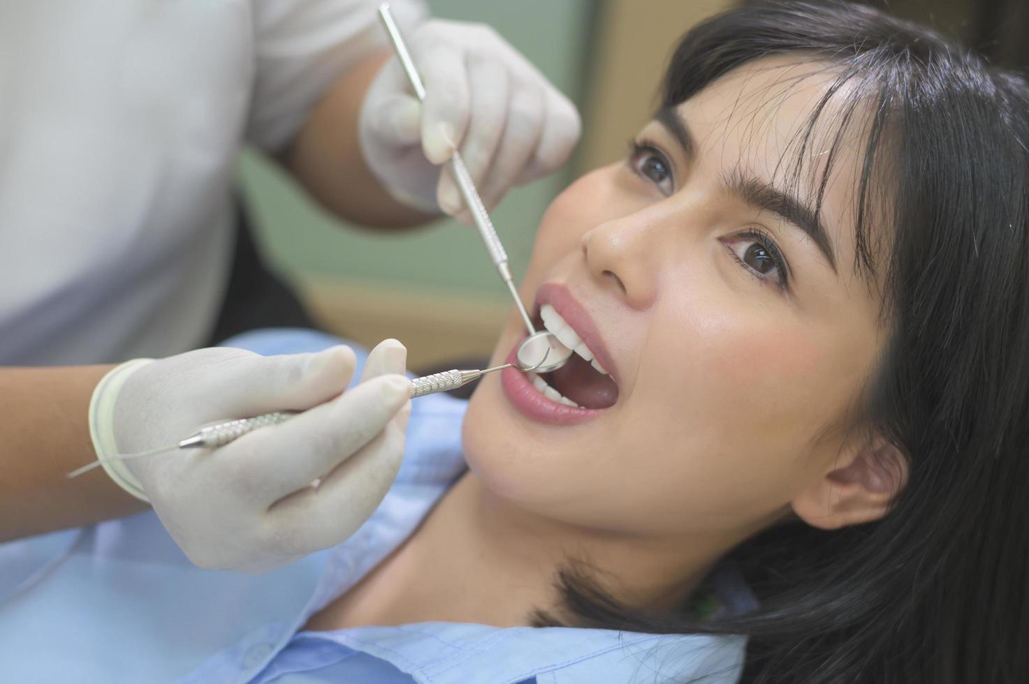 jonge vrouw met tanden onderzocht door tandarts in tandheelkundige kliniek, tandencontrole en gezond gebit concept foto