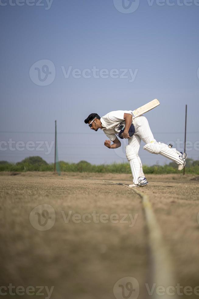 jonge indische cricketspeler die het cricketveld betreedt. Indiase cricket en sport concept. foto