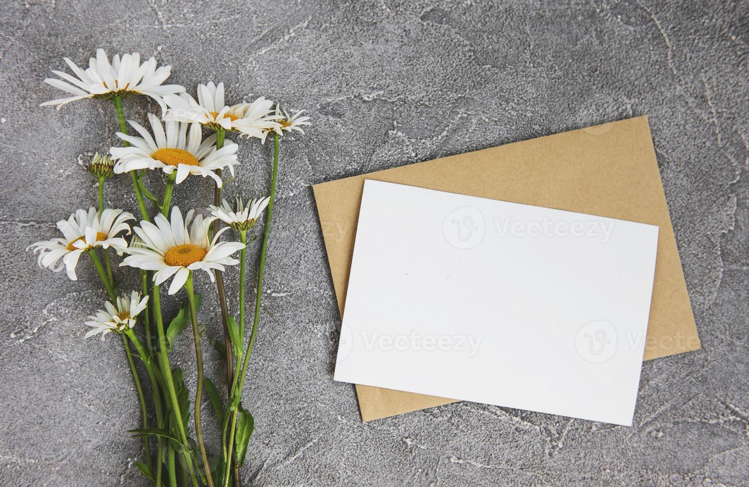 blanco witte wenskaart en envelop met kamillebloemen foto