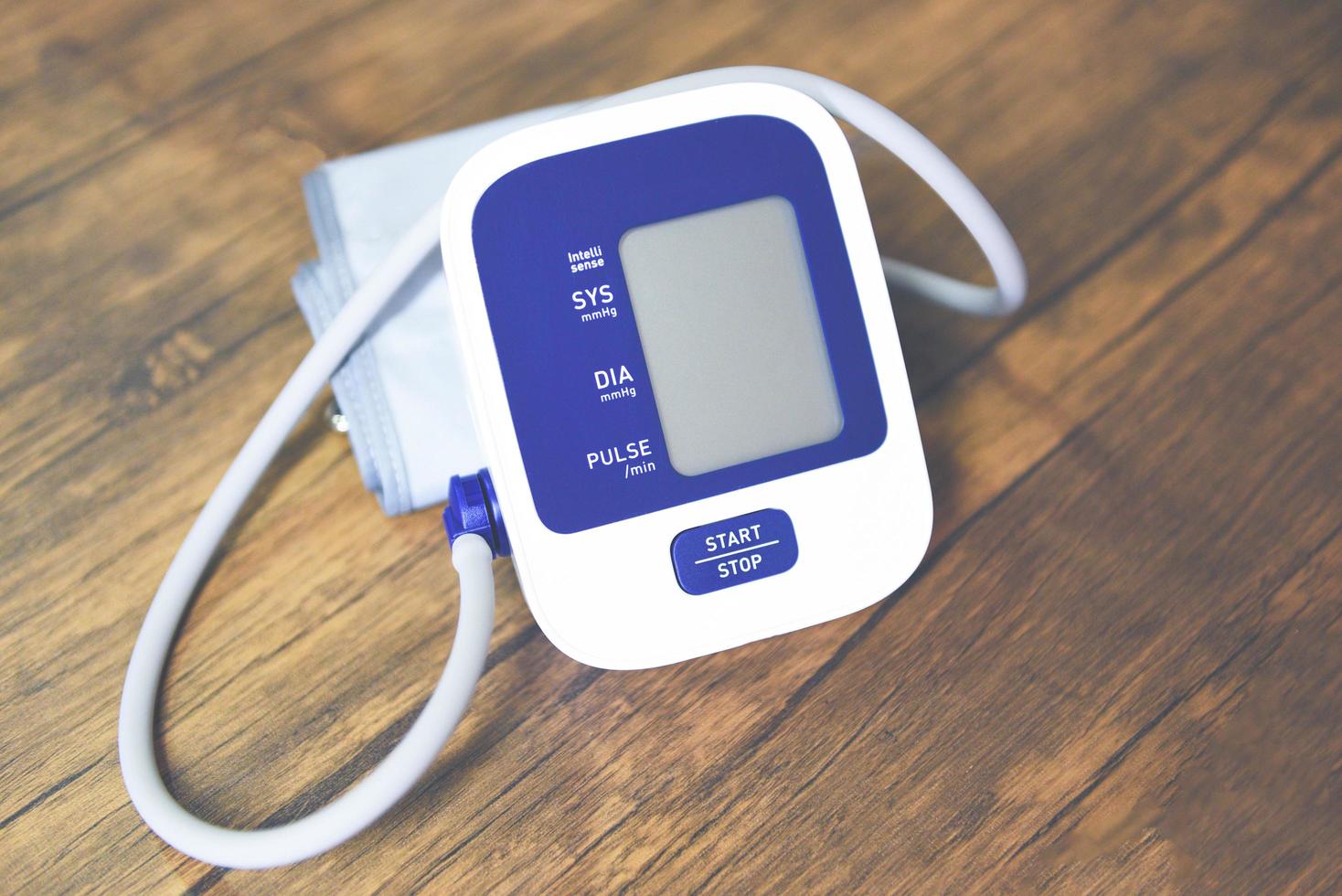 bloeddrukmeter digitaal op houten tafel, medische elektronische tonometer check bloeddruk en hartslag gezondheid en medisch concept. foto