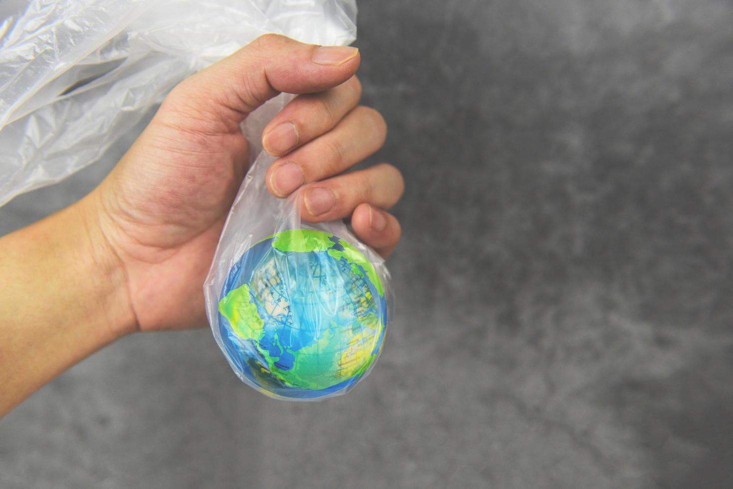 plastic wereld of wereld milieu dag concept - hand houdt de planeet aarde in een plastic zak verbod zeg nee plastic vervuiling nul afval recyclen foto