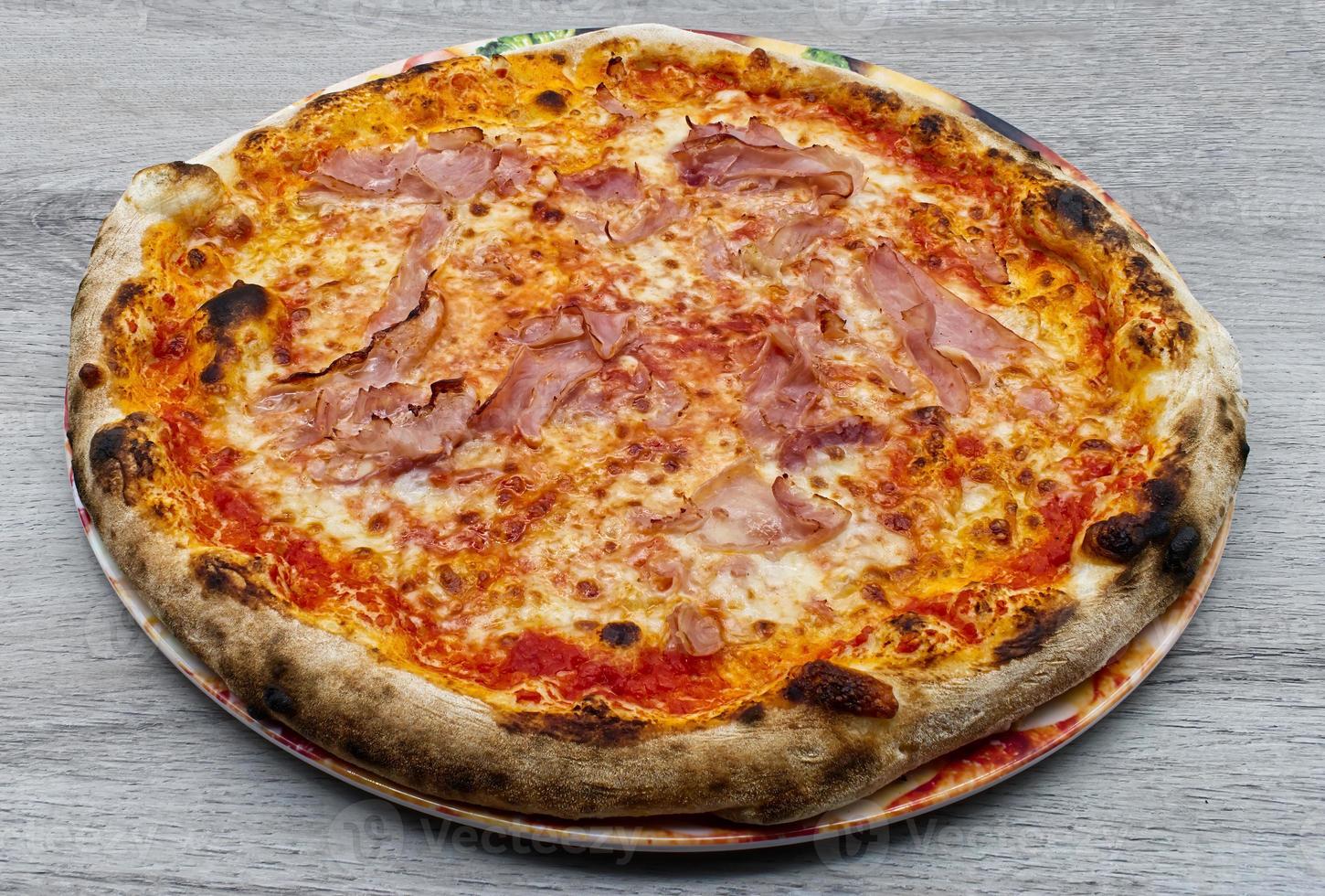 Italiaanse ham en mozzarella kaas pizza op houten achtergrond. foto