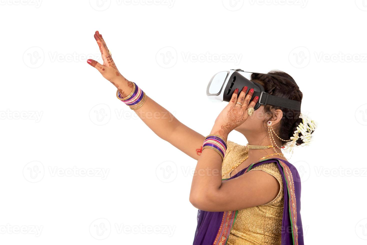 Indiase traditionele jonge vrouw in saree die door een vr-apparaat kijkt foto