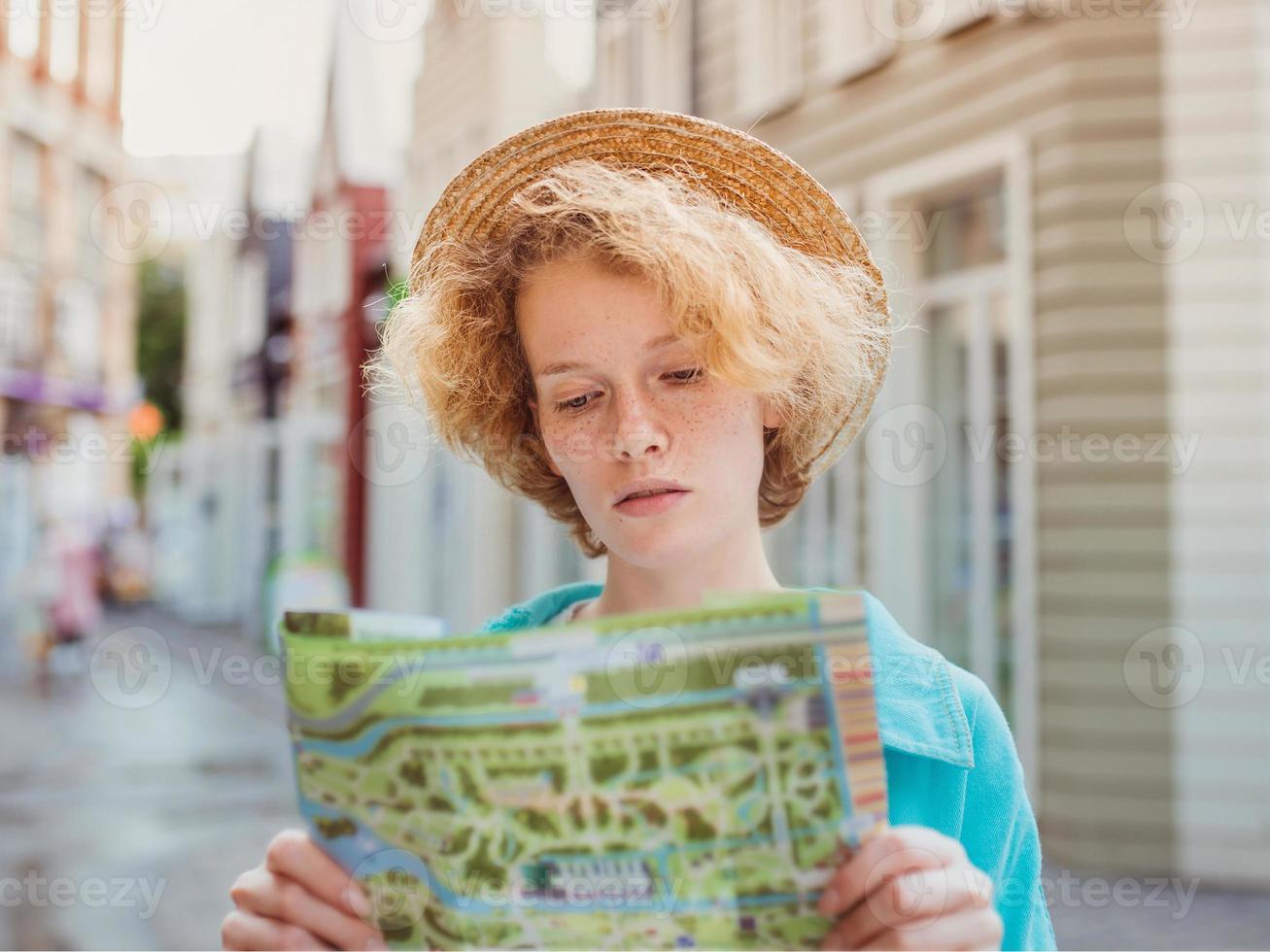 roodharige jonge vrouw reist over West-Europa en gebruikt een papieren kaart in een onbekende stad. reis foto. verloren in nieuwe stad foto