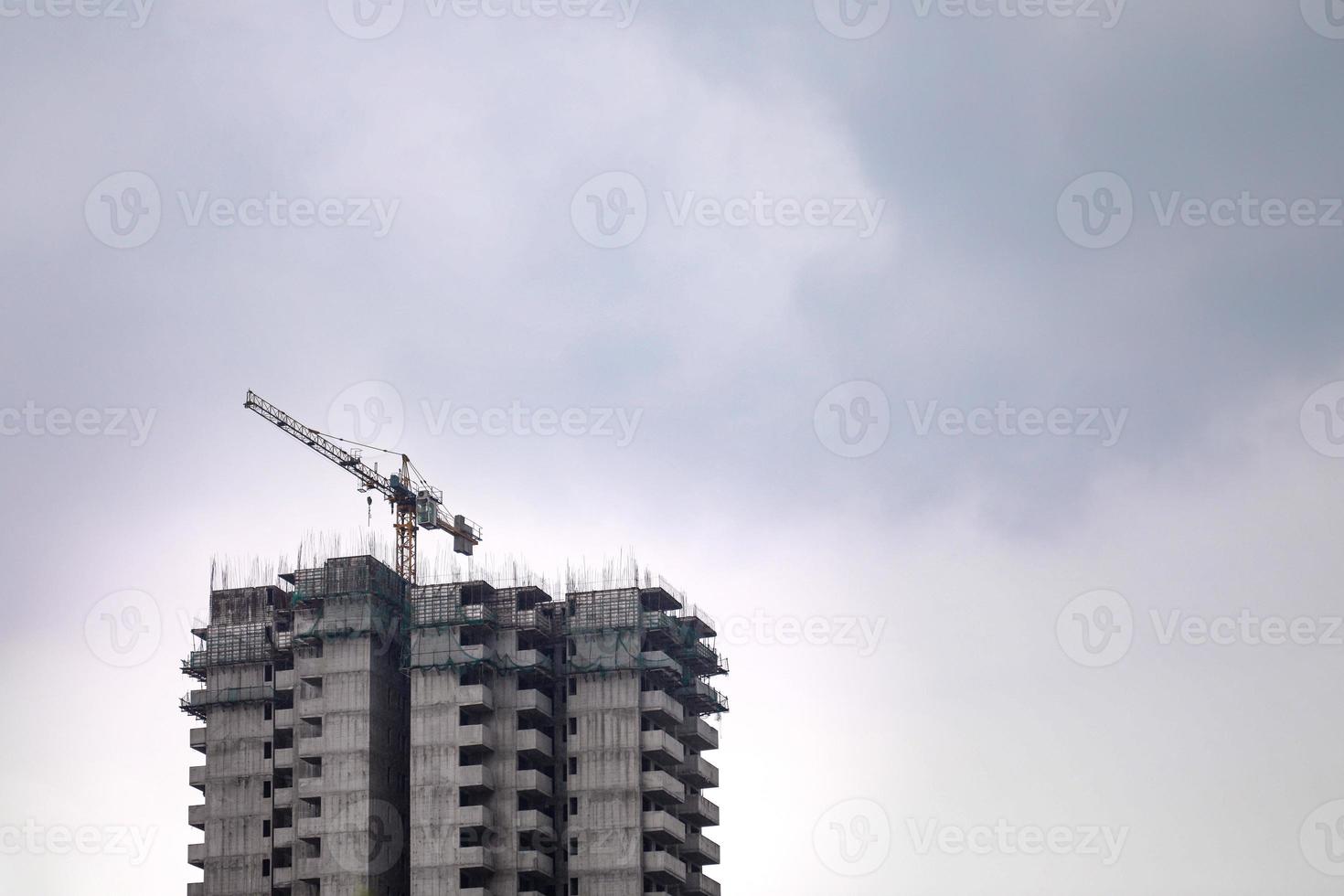 zware lastkraan bovenop een gebouw tegen de bewolkte hemel, met kopieerruimte. foto