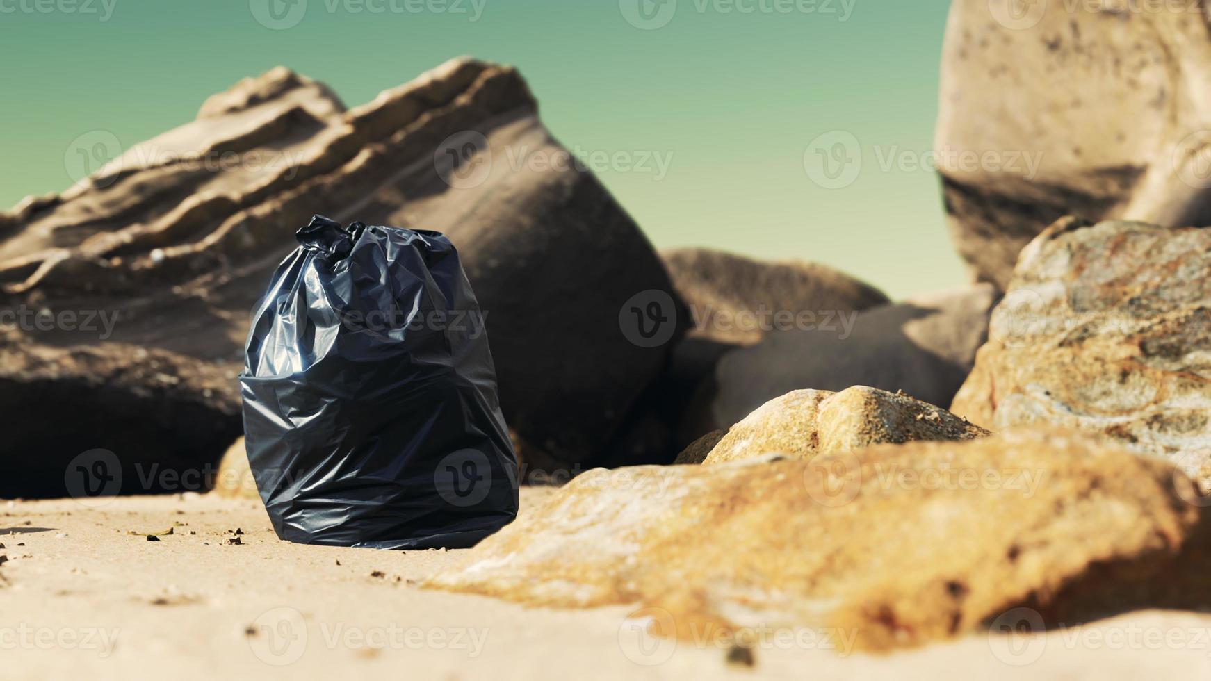 zwarte plastic vuilniszak vol afval op het strand foto