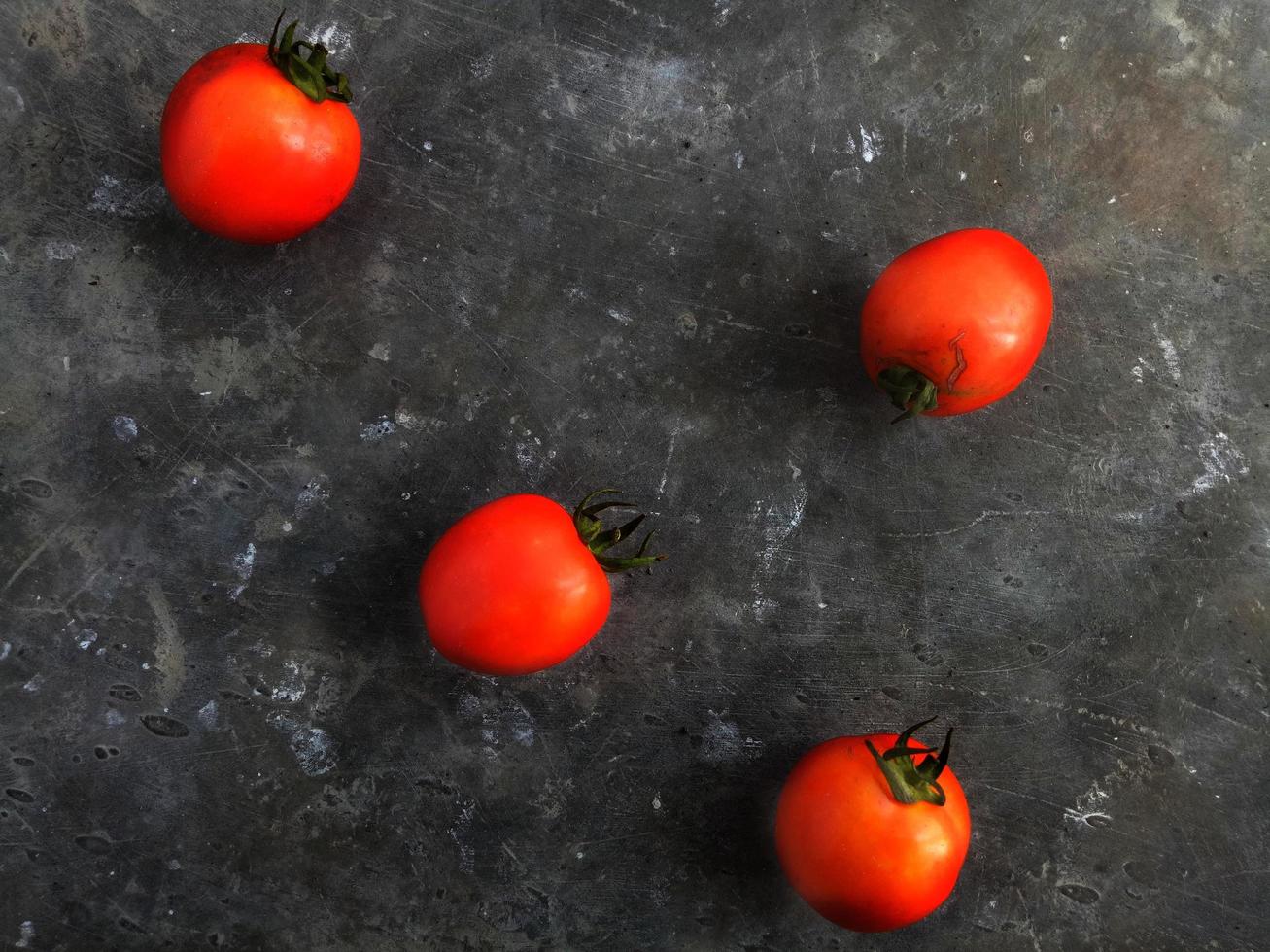 4 tomaten op de foto van bovenaf met een grijze achtergrond met patroon