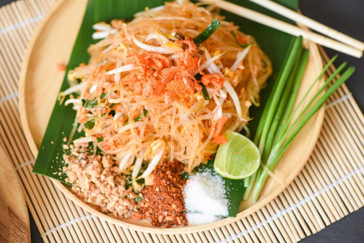 roerbak noodle pad thai op bord geserveerd op de eettafel eten, thais eten gebakken noedel thaise stijl met garnalen taugé en garnituur pinda's chili poeder suiker citroen limoen - bovenaanzicht foto