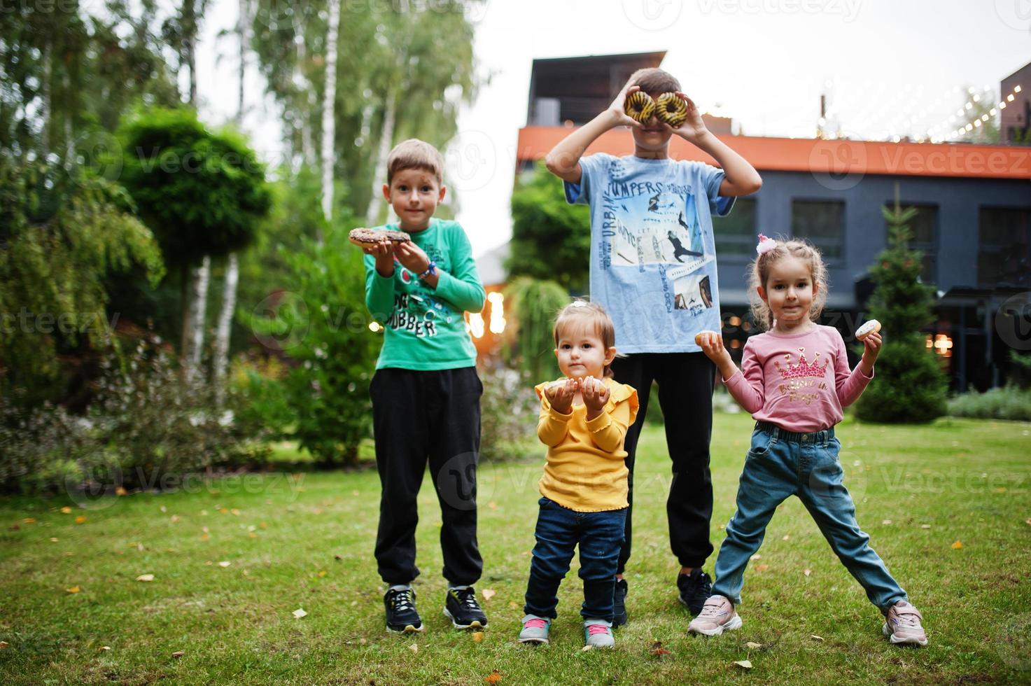 vier kinderen met donuts op de avondtuin. lekker lekker donut eten. foto