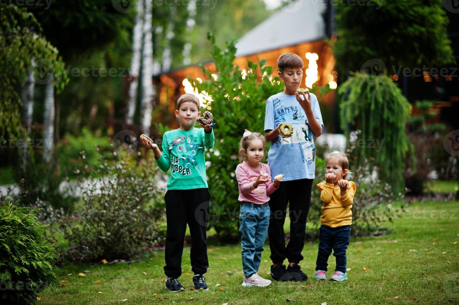 vier kinderen met donuts op de avondtuin. lekker lekker donut eten. foto