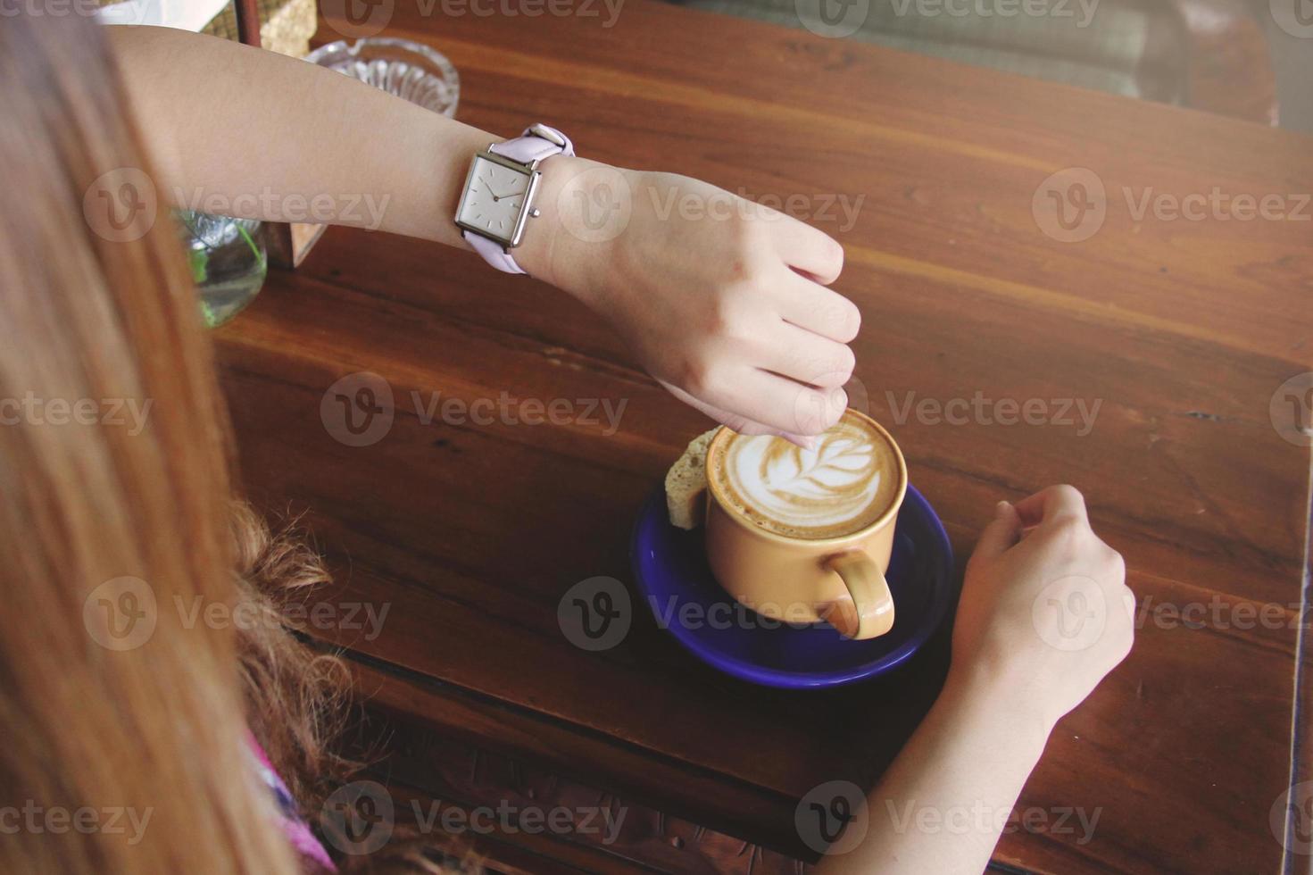 vrouw zitten met een kopje koffie op de houten tafel. zachte focus foto. wachten op iemand concept foto