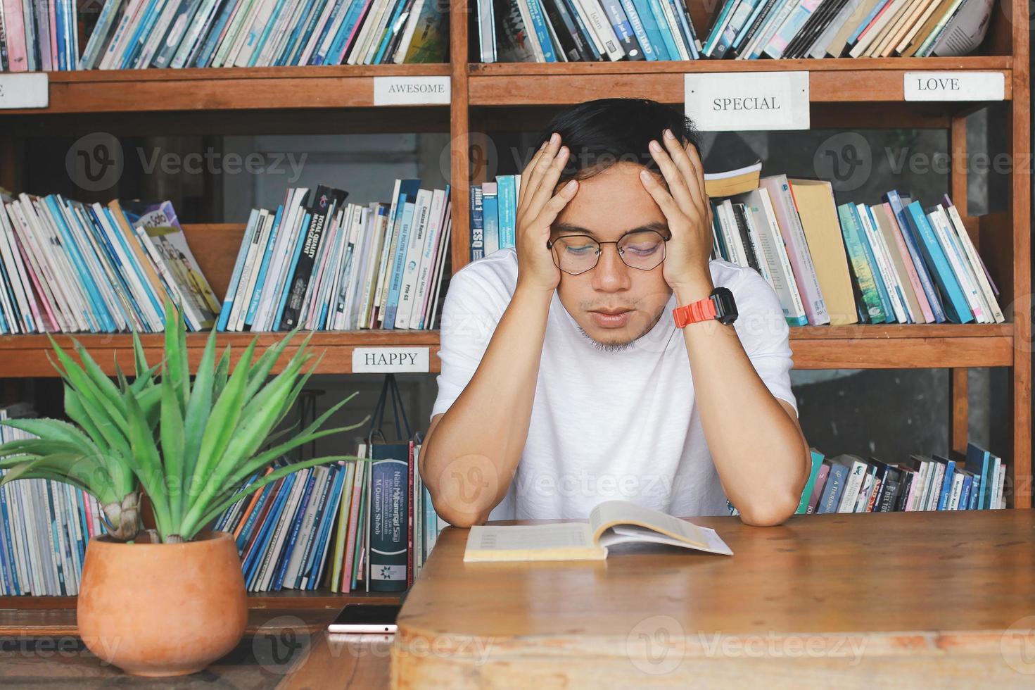 jonge student man leest een boek in de bibliotheek serieus, bandung, indonesië 2 september 2020 foto