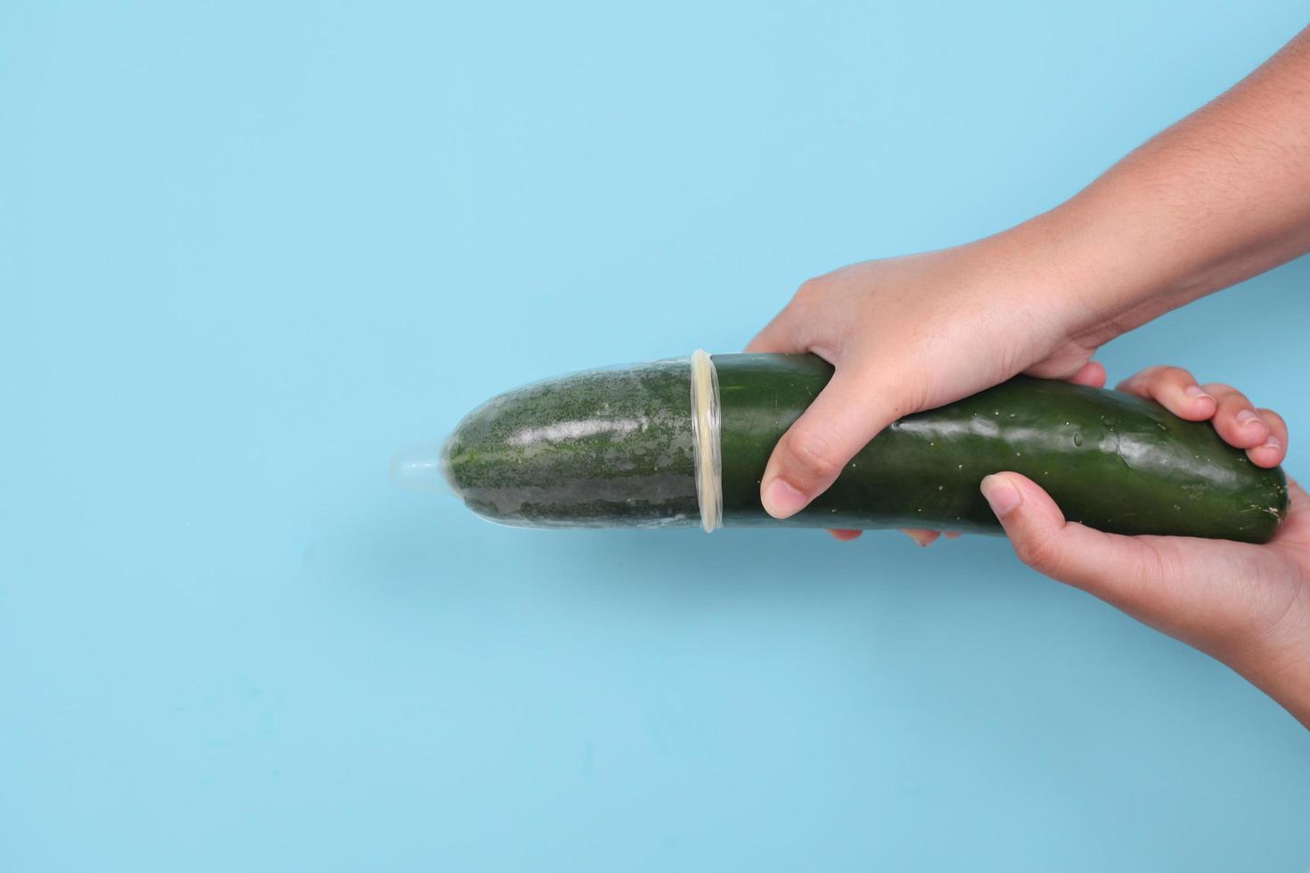 seksuele voorlichting met komkommer en anticonceptie geïsoleerd op blauwe achtergrond foto