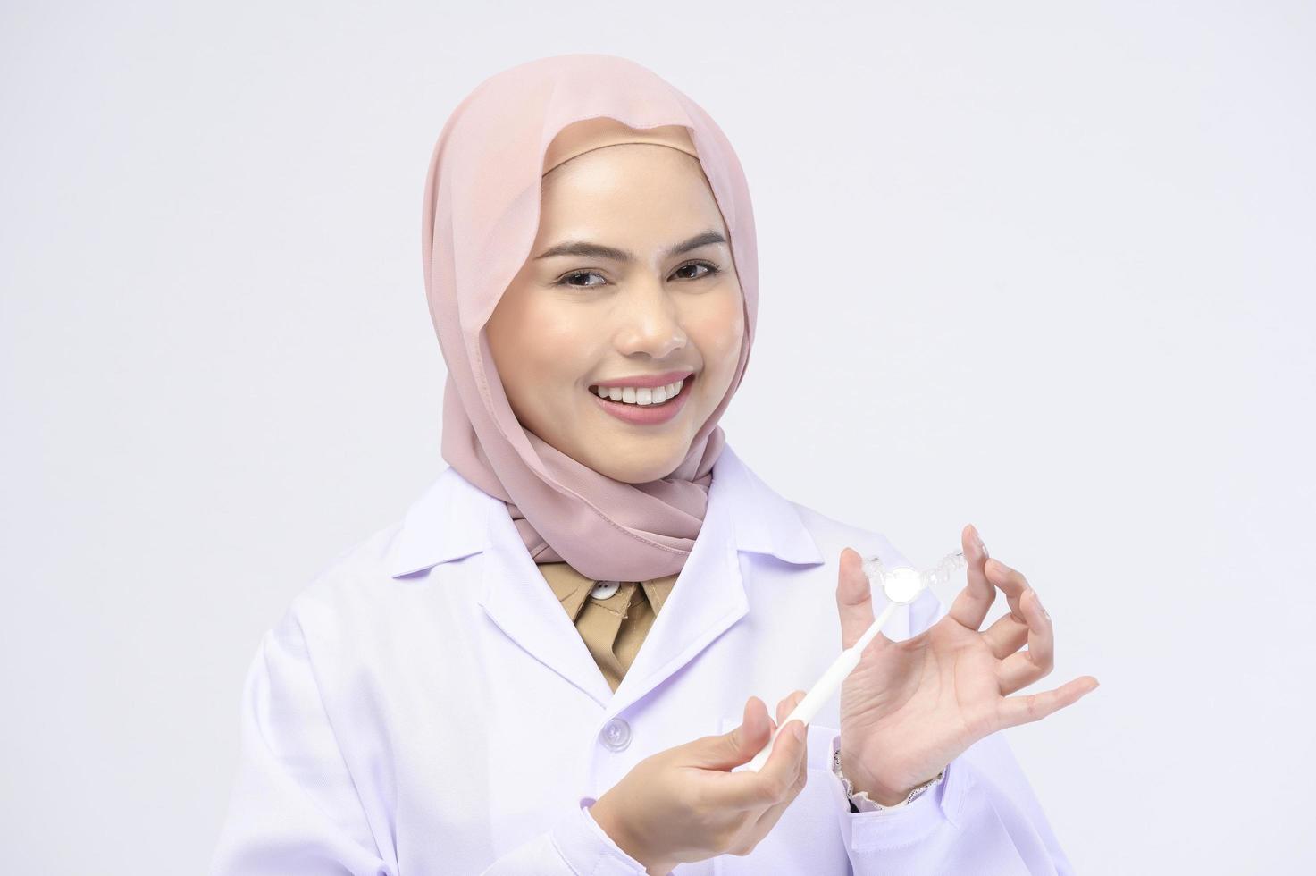 moslim vrouwelijke tandarts met invisalign beugels over witte achtergrond studio, tandheelkundige gezondheidszorg en orthodontische concept. foto