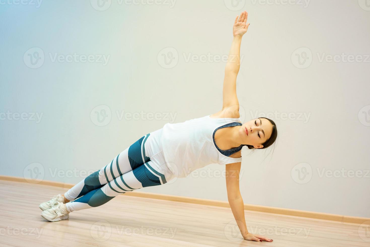 een jonge vrouw is thuis op de mat bezig met fitness foto