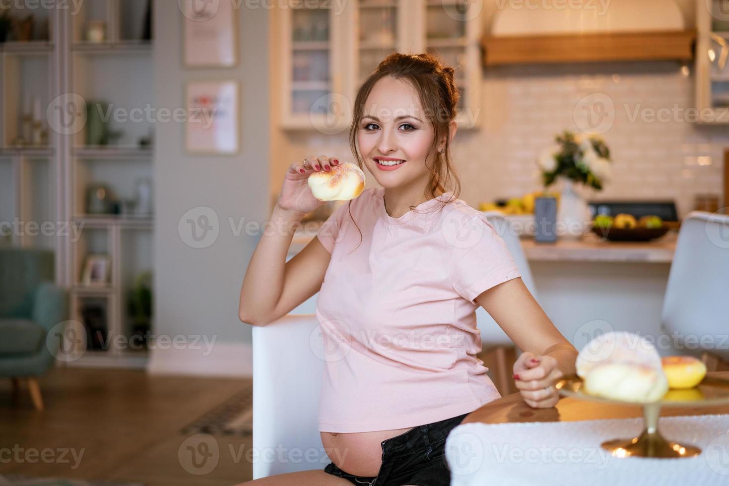 gelukkige jonge zwangere vrouw met cake in de hand foto