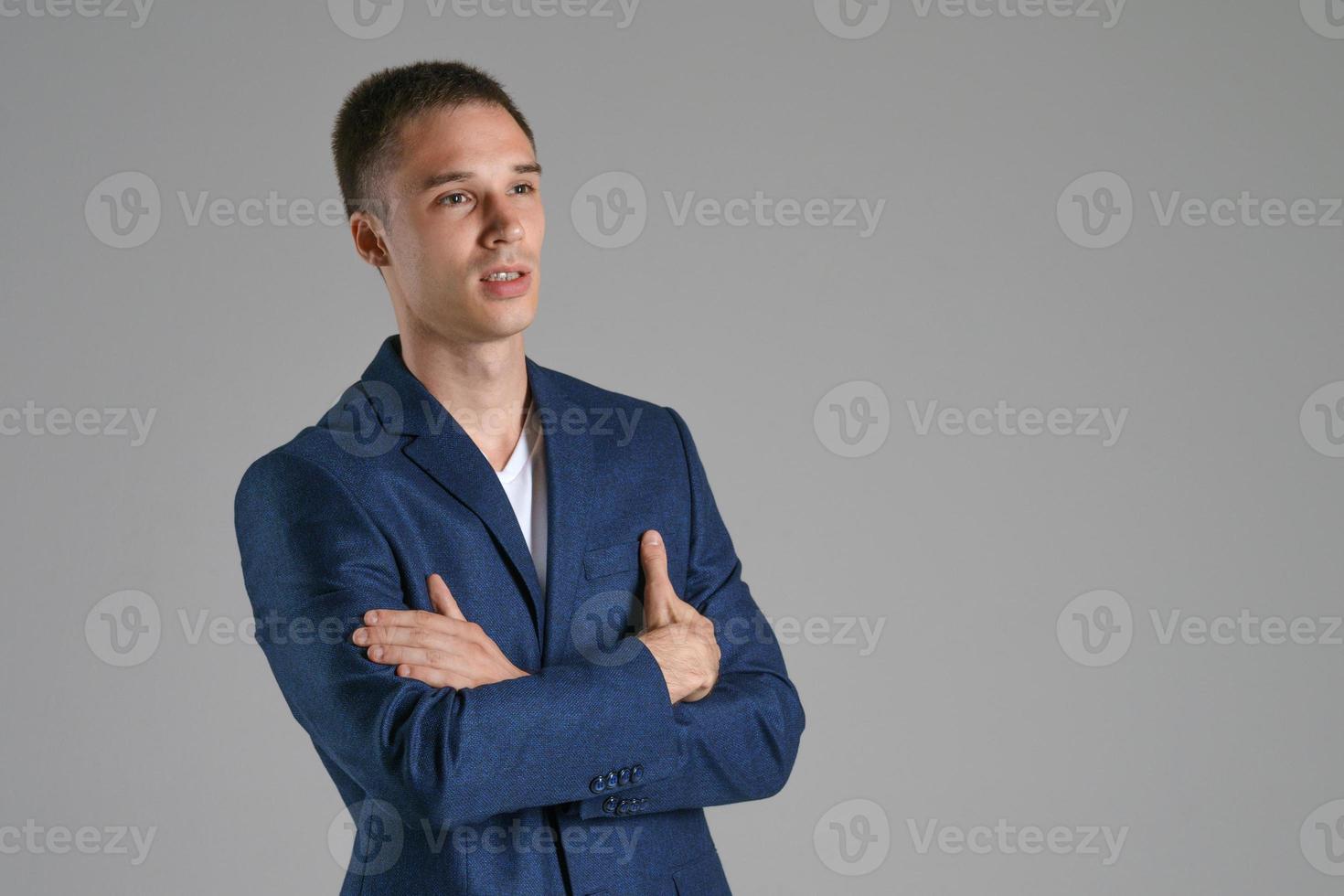 een jonge zakenman in een blauwe jas op een grijze achtergrond foto