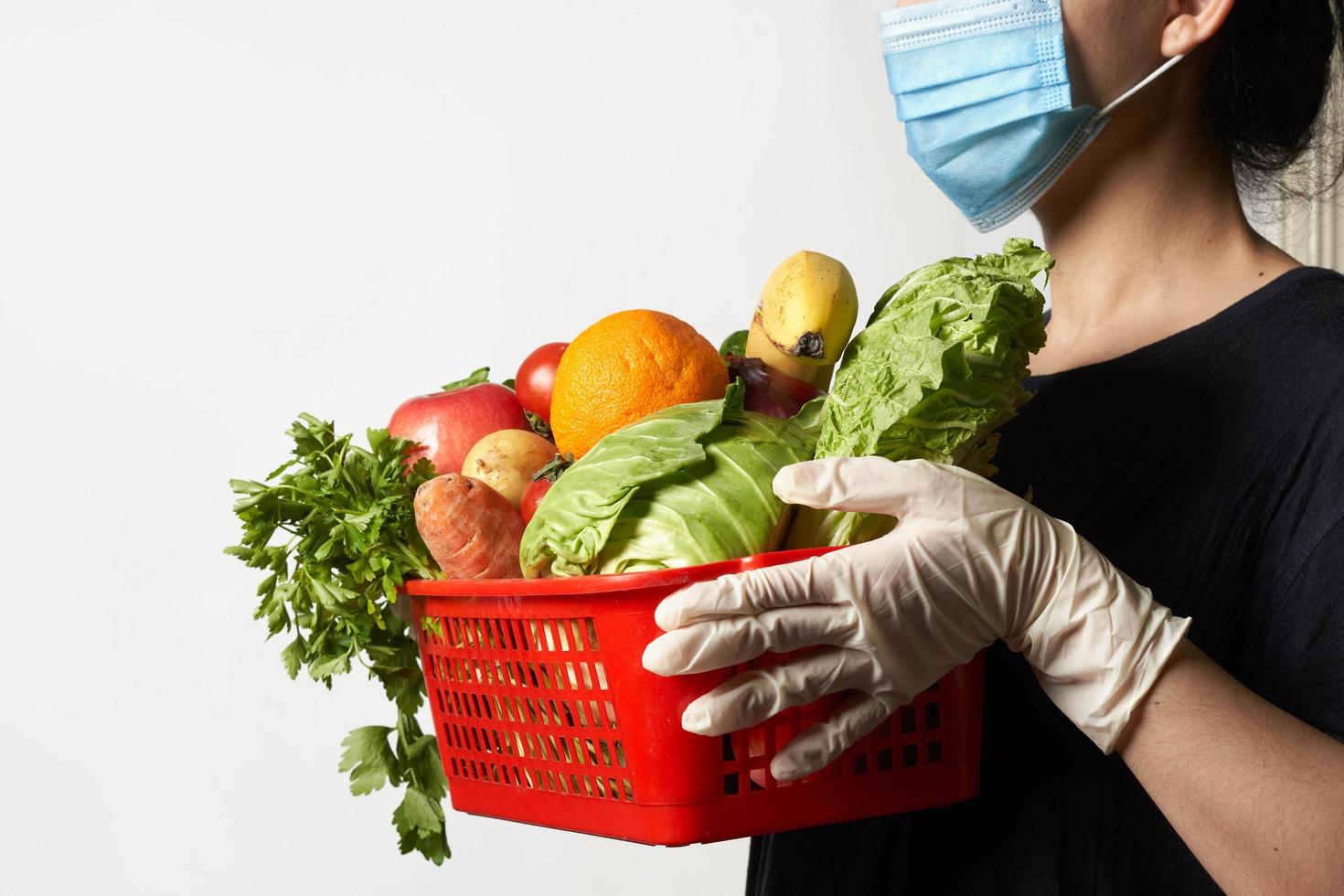 bezorger met gezichtsmasker en medische handschoenen brengt bestelde verse groenten foto