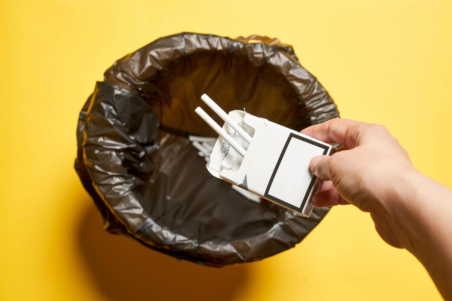 een vrouw die sigarettenzak in de vuilnisbak gooit - concept van stoppen met roken foto