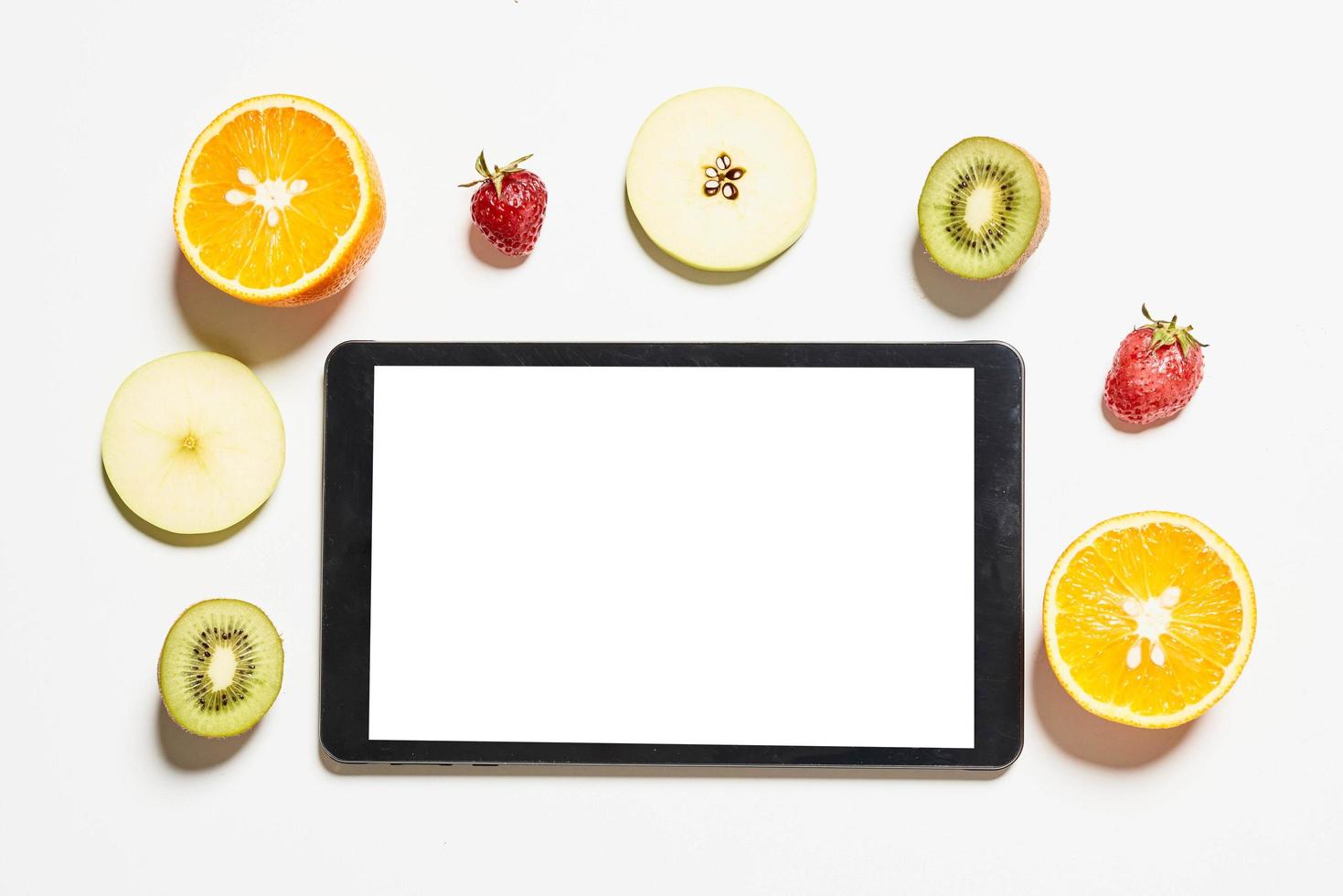 tablet met leeg wit scherm en verschillende plakjes fruit eromheen foto