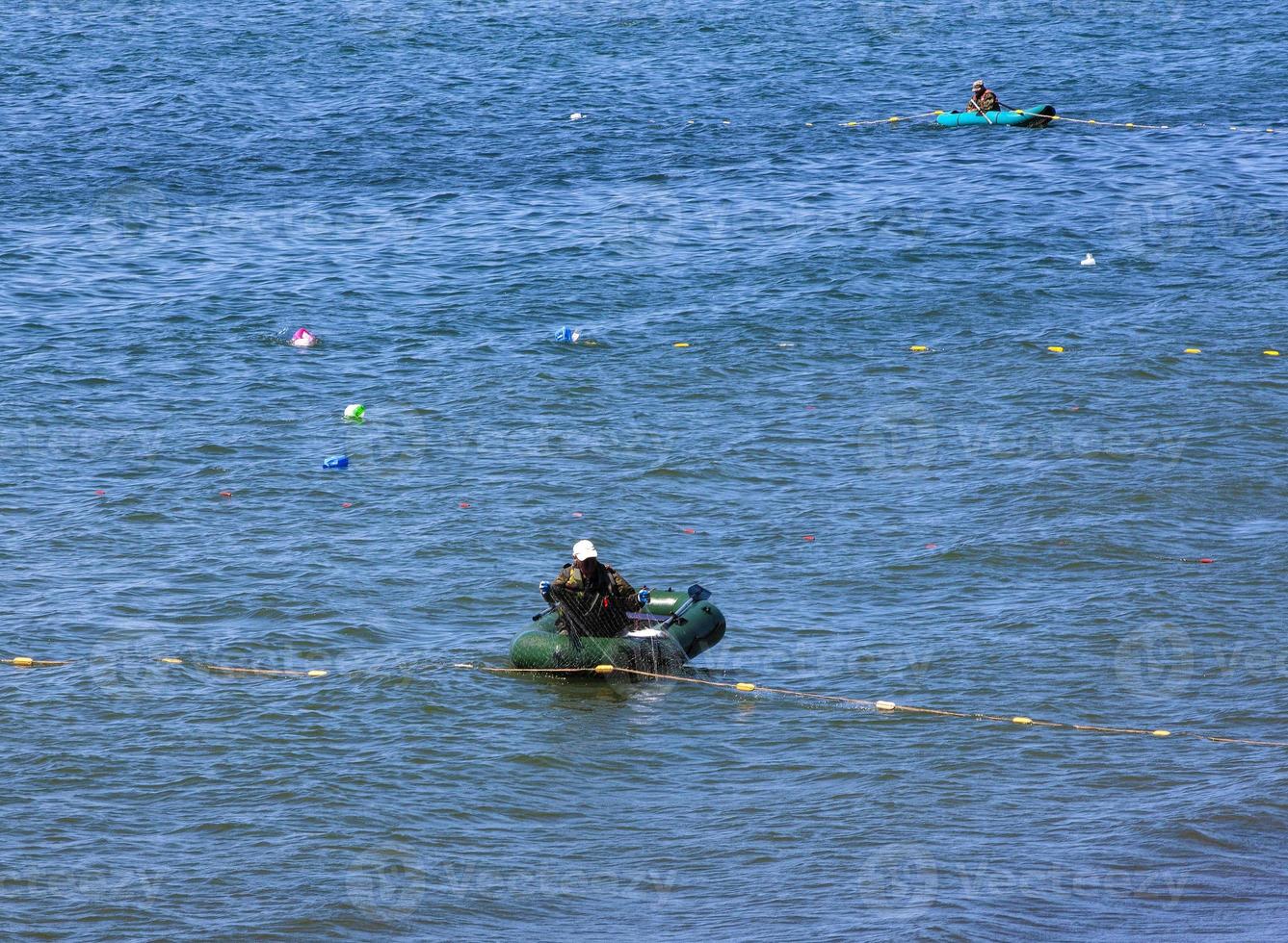 de visser op rubberboot vangt zalmnetwerk op de Stille Oceaan foto