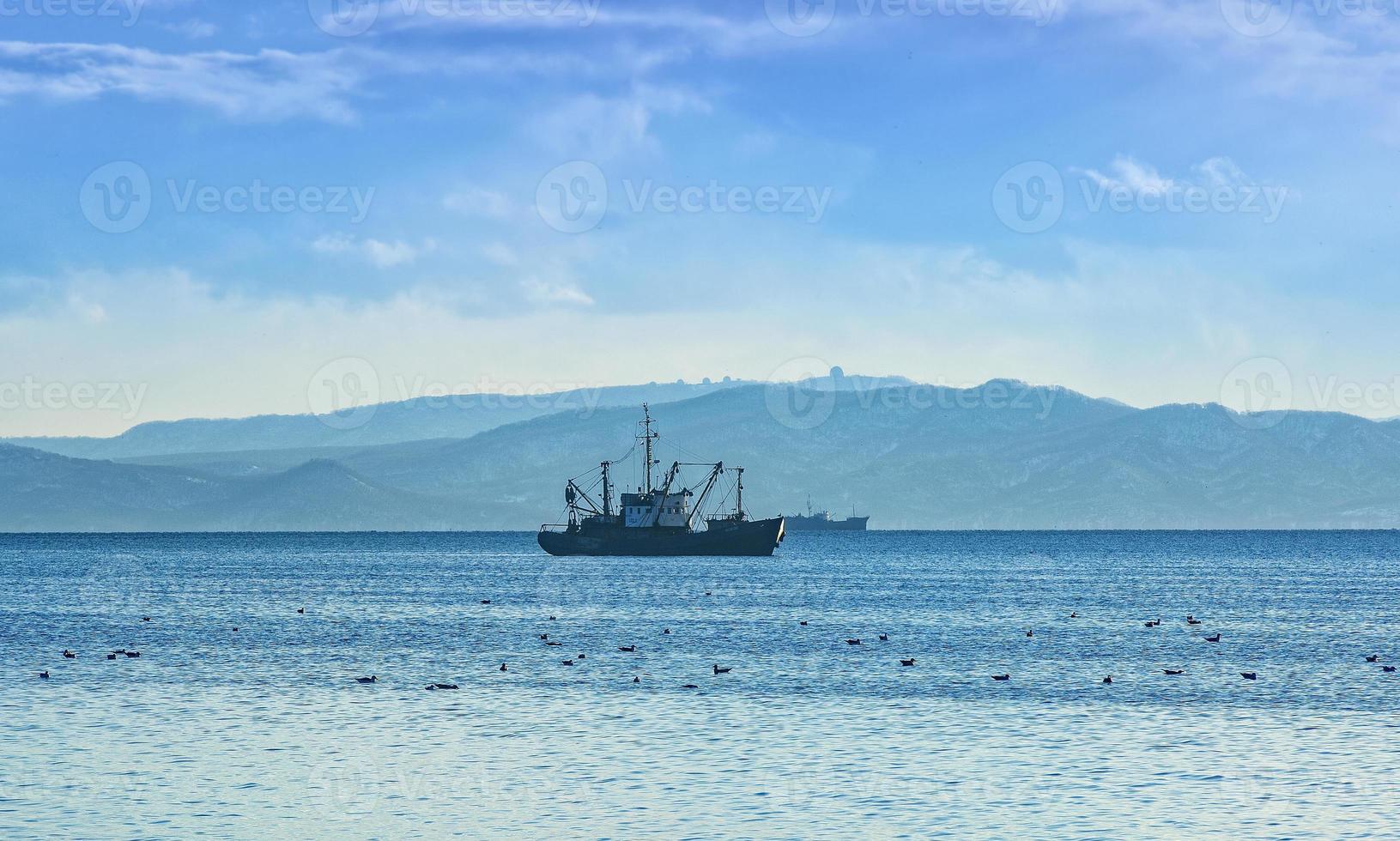 vissersboot in grijze ochtend op de Stille Oceaan voor de kust van het schiereiland Kamtsjatka foto