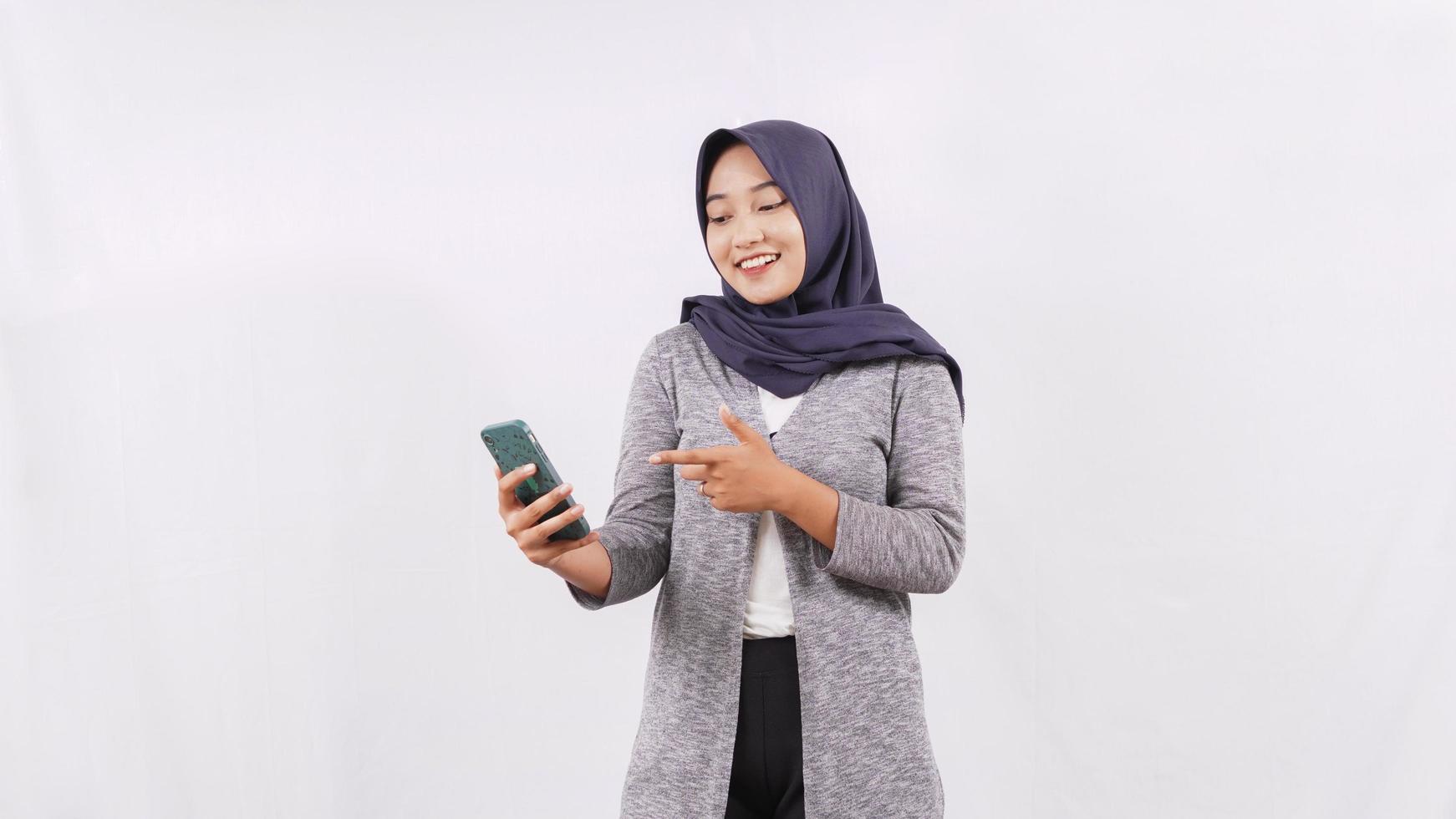 jonge aziatische vrouw die smartphone speelt die gelukkig op witte achtergrond wordt geïsoleerd foto