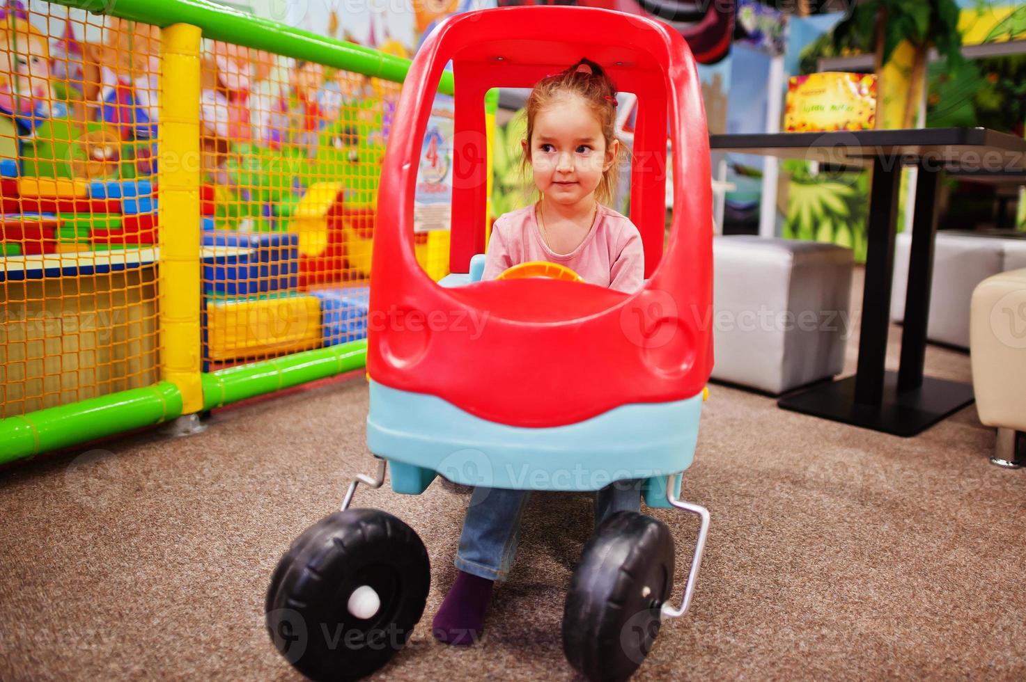 schattige babymeisje rijdt op een plastic auto in indoor speelcentrum. foto