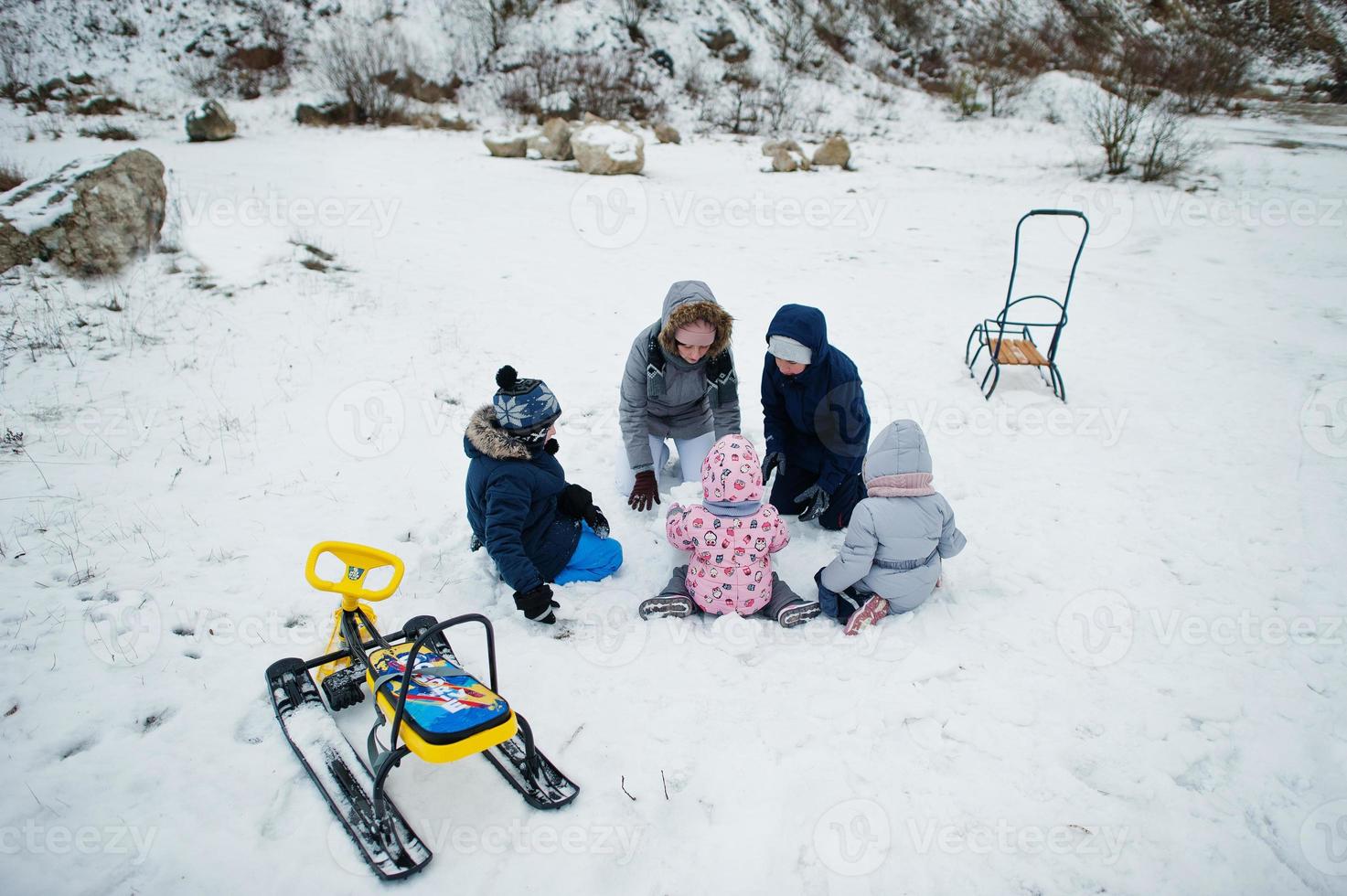 familie speelt en sleeën in de winter buiten, moeder en kinderen hebben plezier. foto