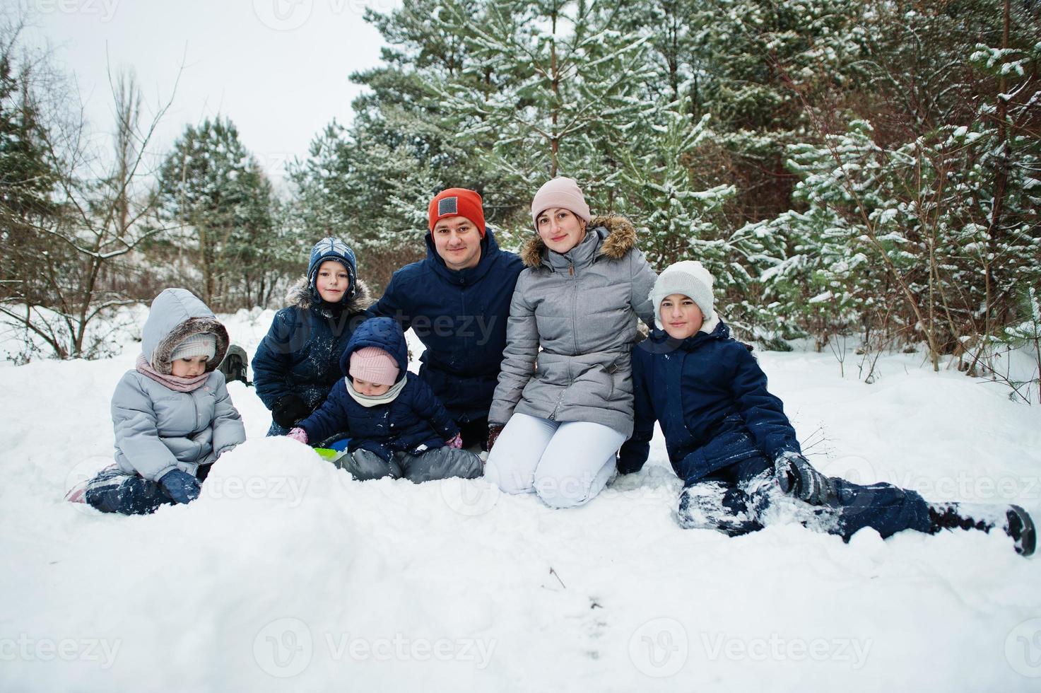 vader en moeder met vier kinderen in de winternatuur. buiten in de sneeuw. foto