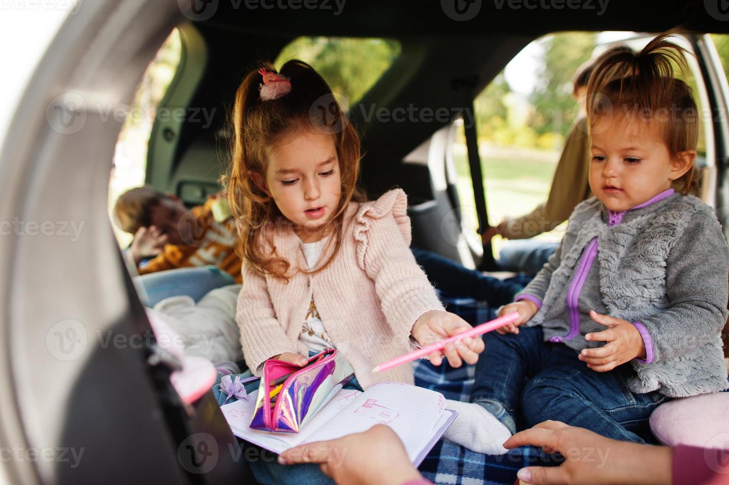 moeder met vier kinderen bij voertuiginterieur. kinderen in de kofferbak. reizen met de auto, liegen en plezier maken, sfeerconcept. foto